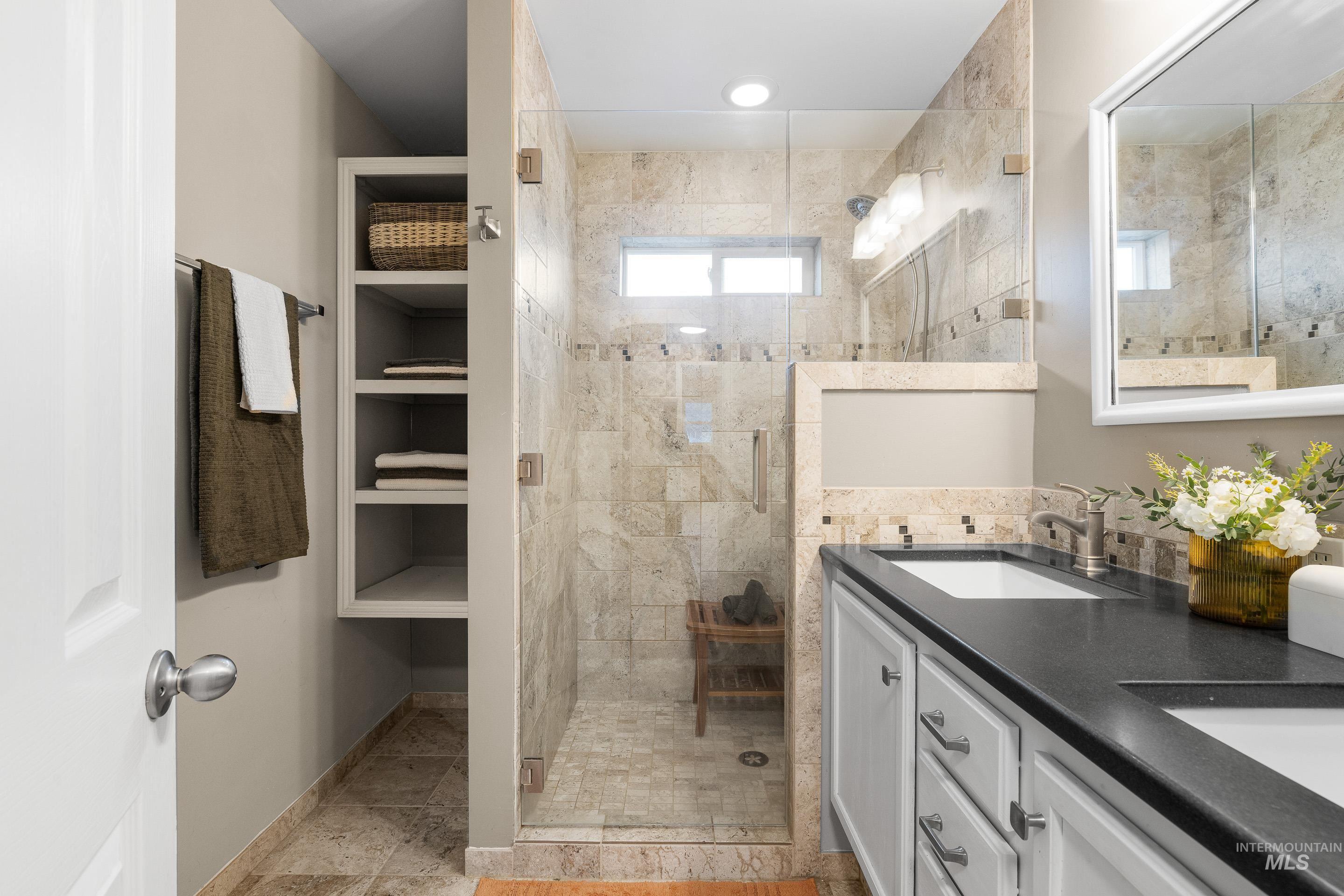 Full bathroom with double vanity and a shower stall