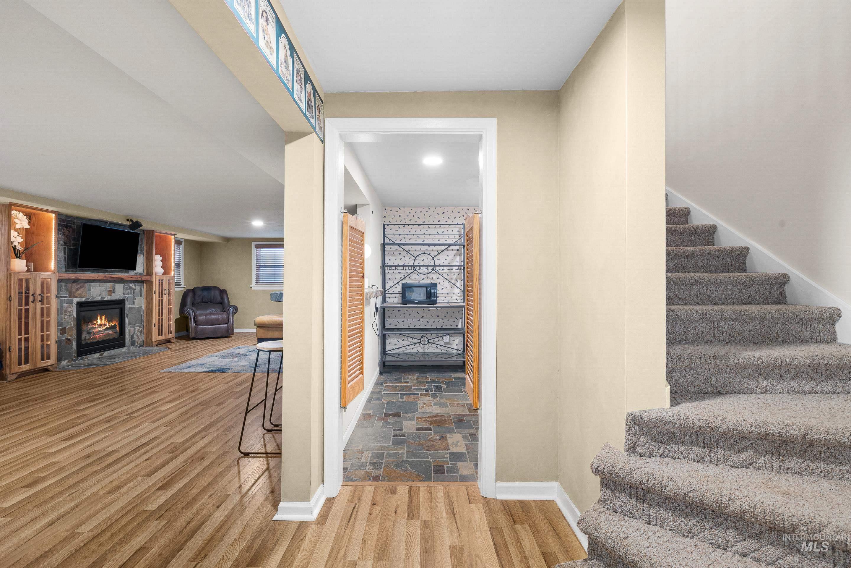 Stairs with a glass covered fireplace and wood finished floors