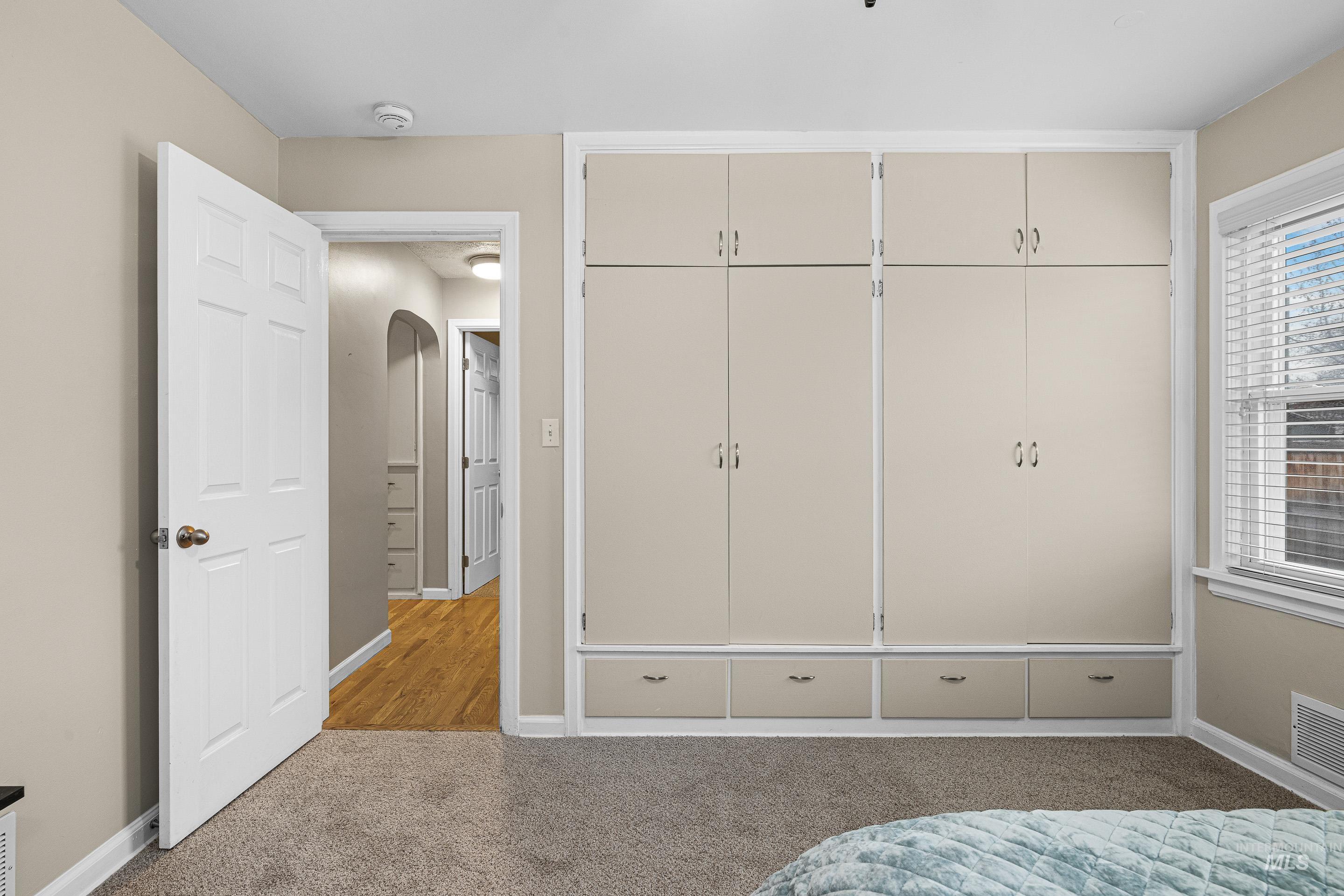 Bedroom featuring a closet, light colored carpet, and arched walkways