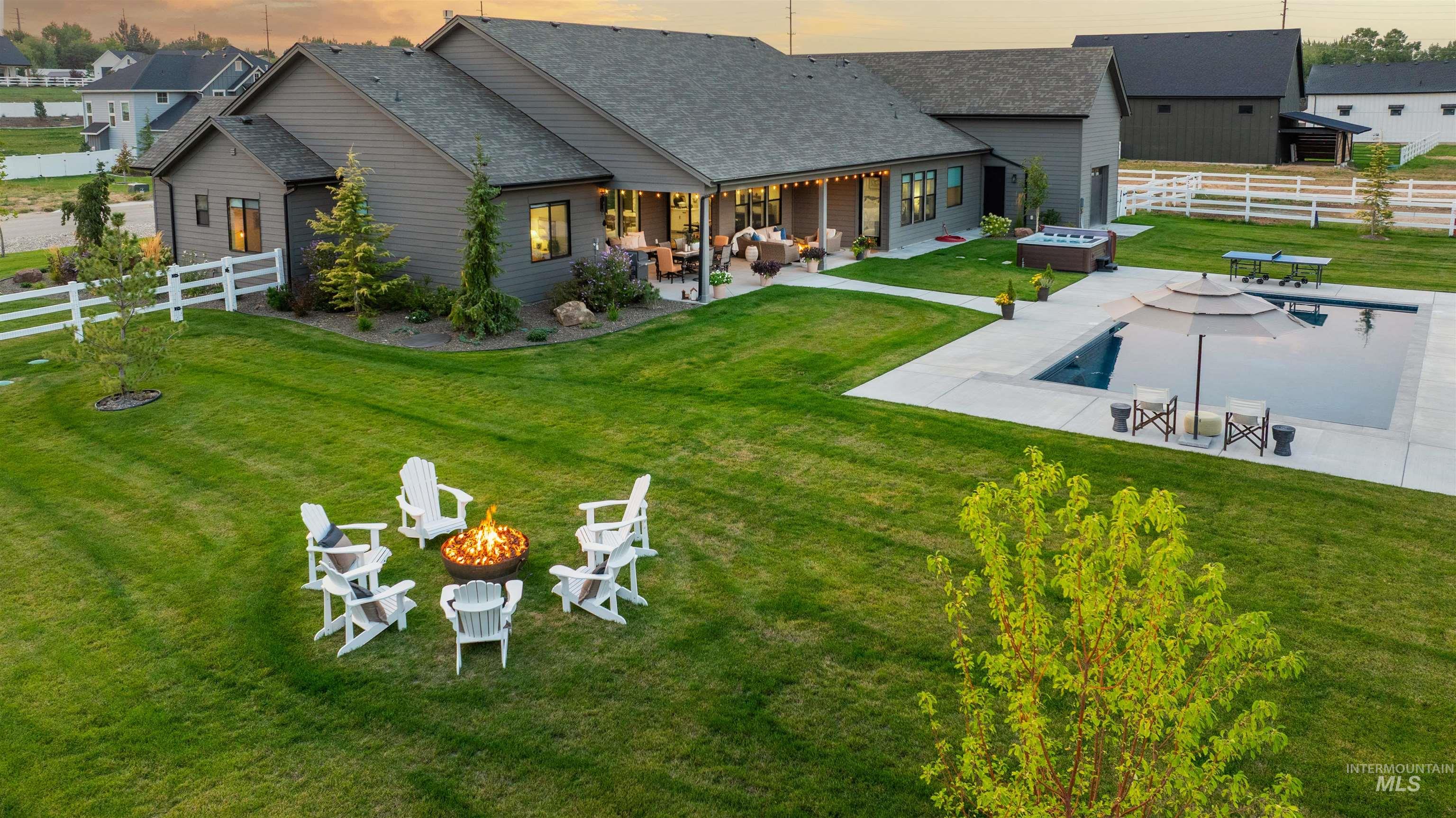 Back of house with a fenced backyard, a patio area, an outdoor living space with a fire pit, and roof with shingles
