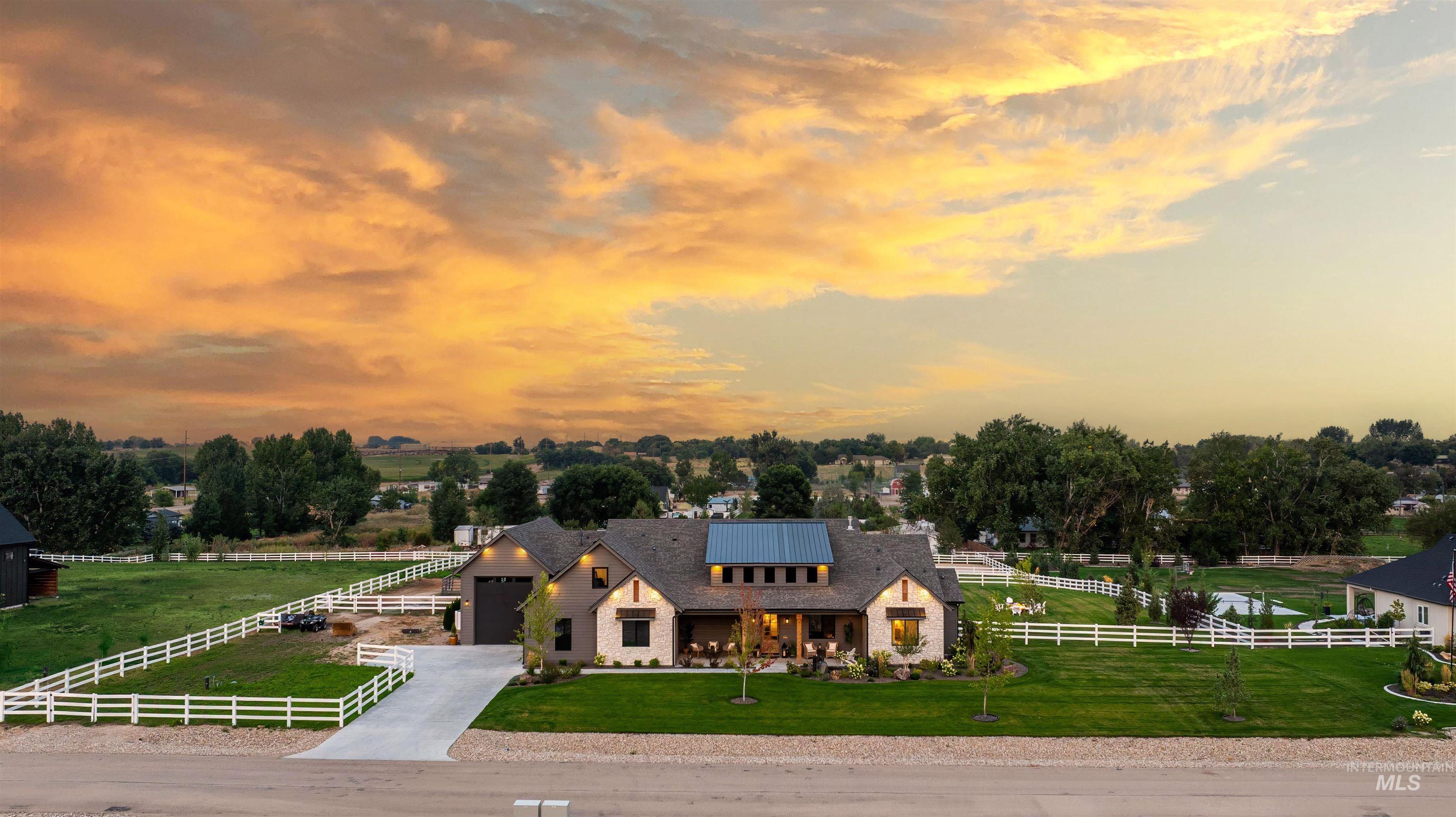 View of front of house with driveway, a view of rural / pastoral area, an attached garage, and roof mounted solar panels