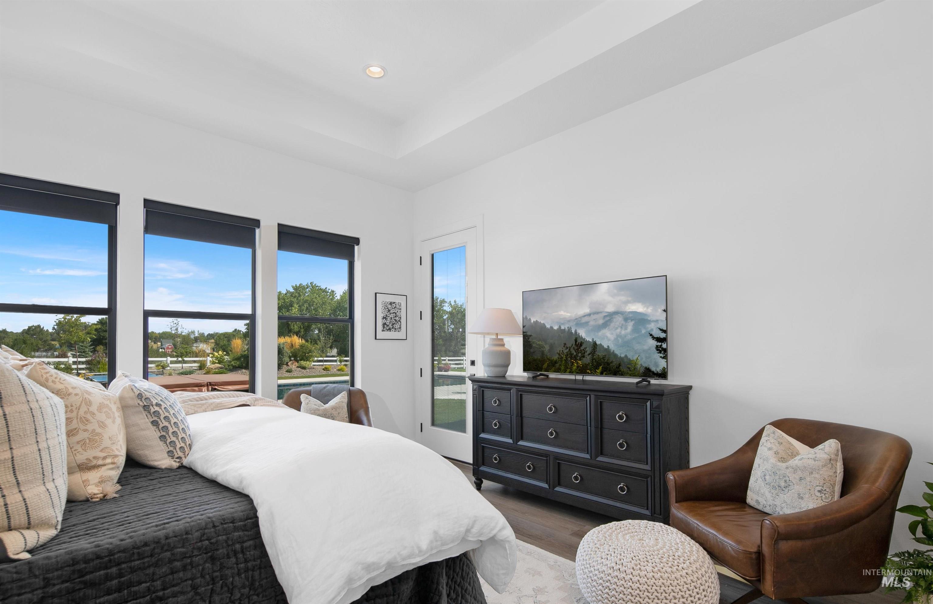 Bedroom with wood finished floors, recessed lighting, and a tray ceiling