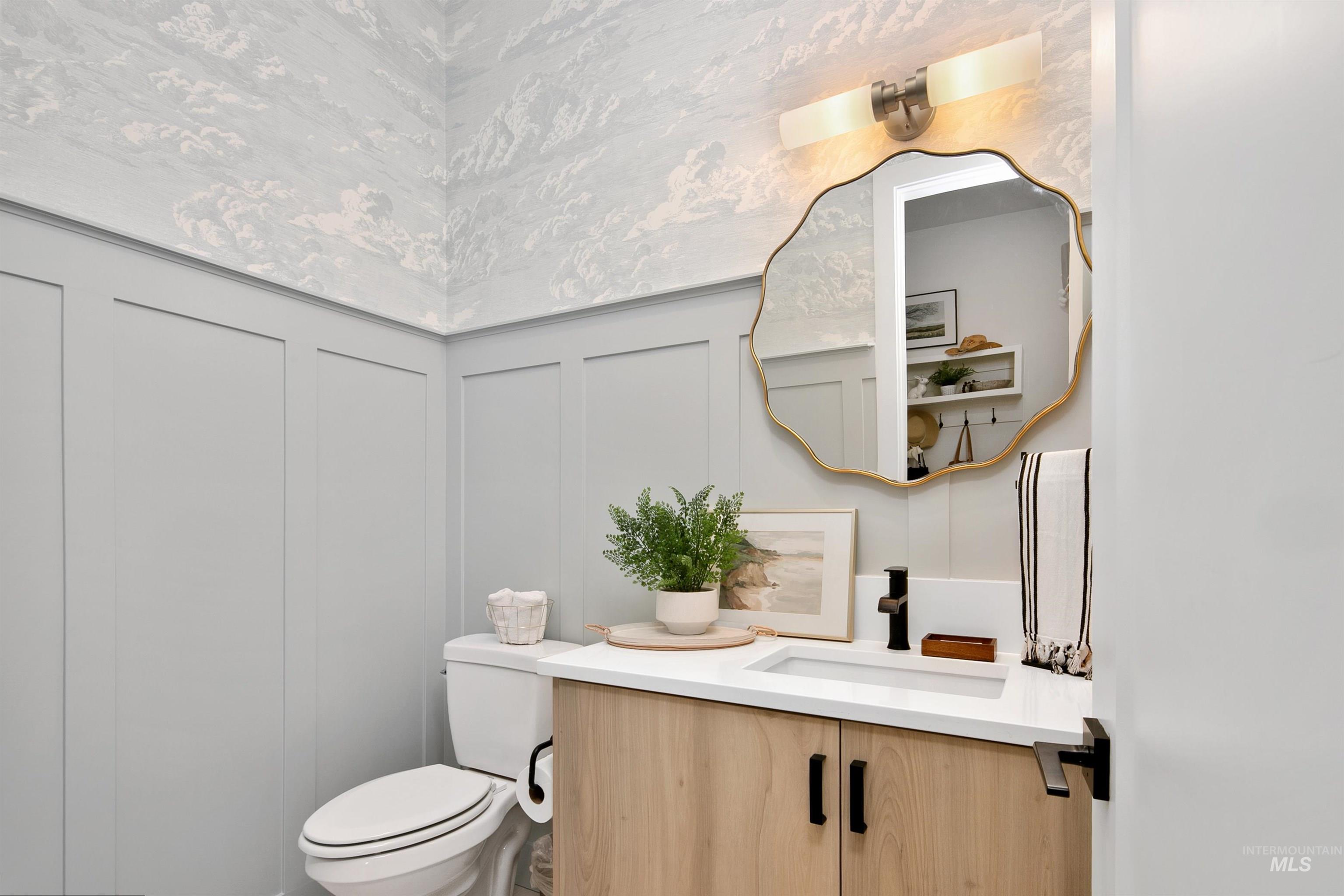 Bathroom featuring a decorative wall, vanity, and wainscoting