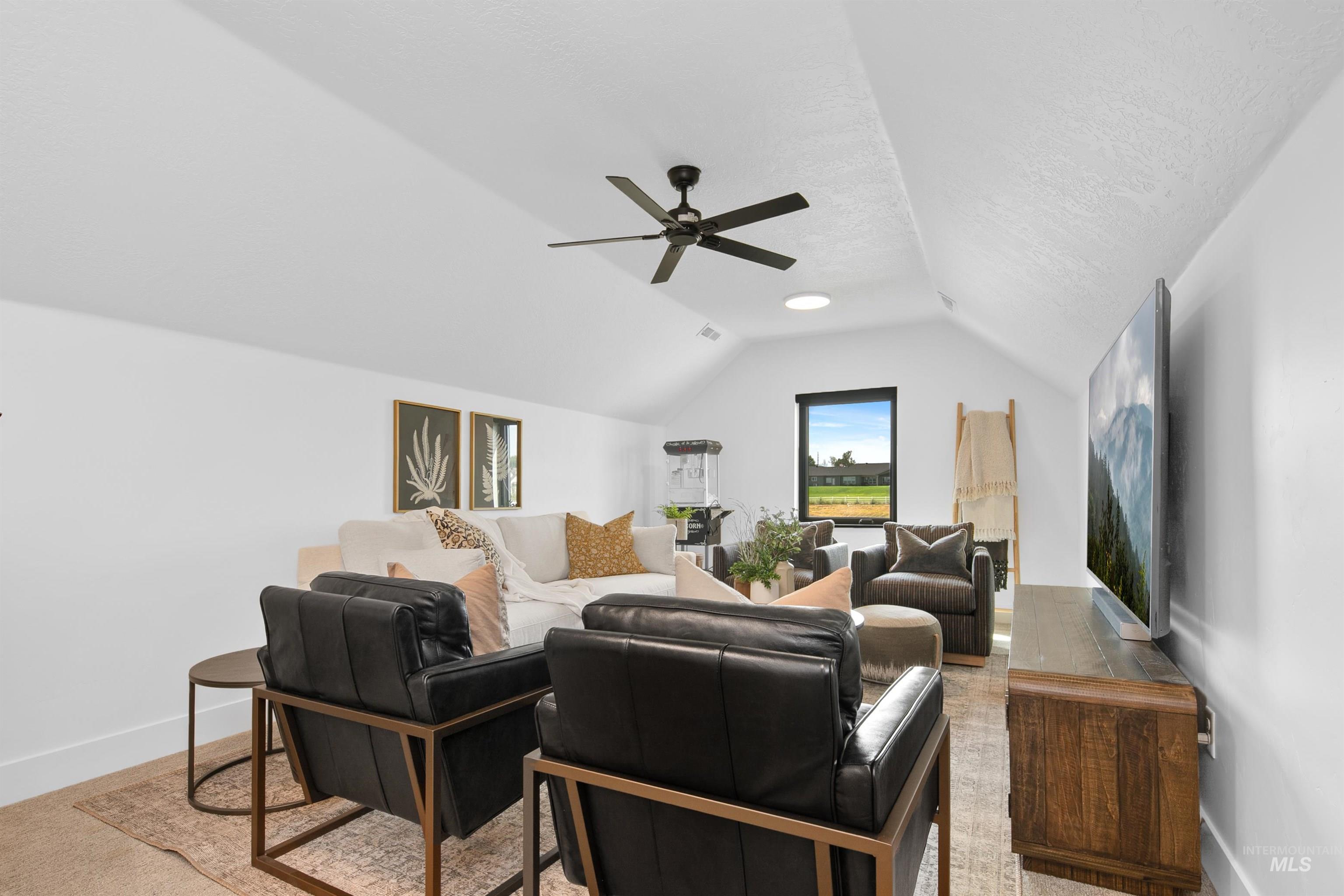 Living room with lofted ceiling, a ceiling fan, and a textured ceiling