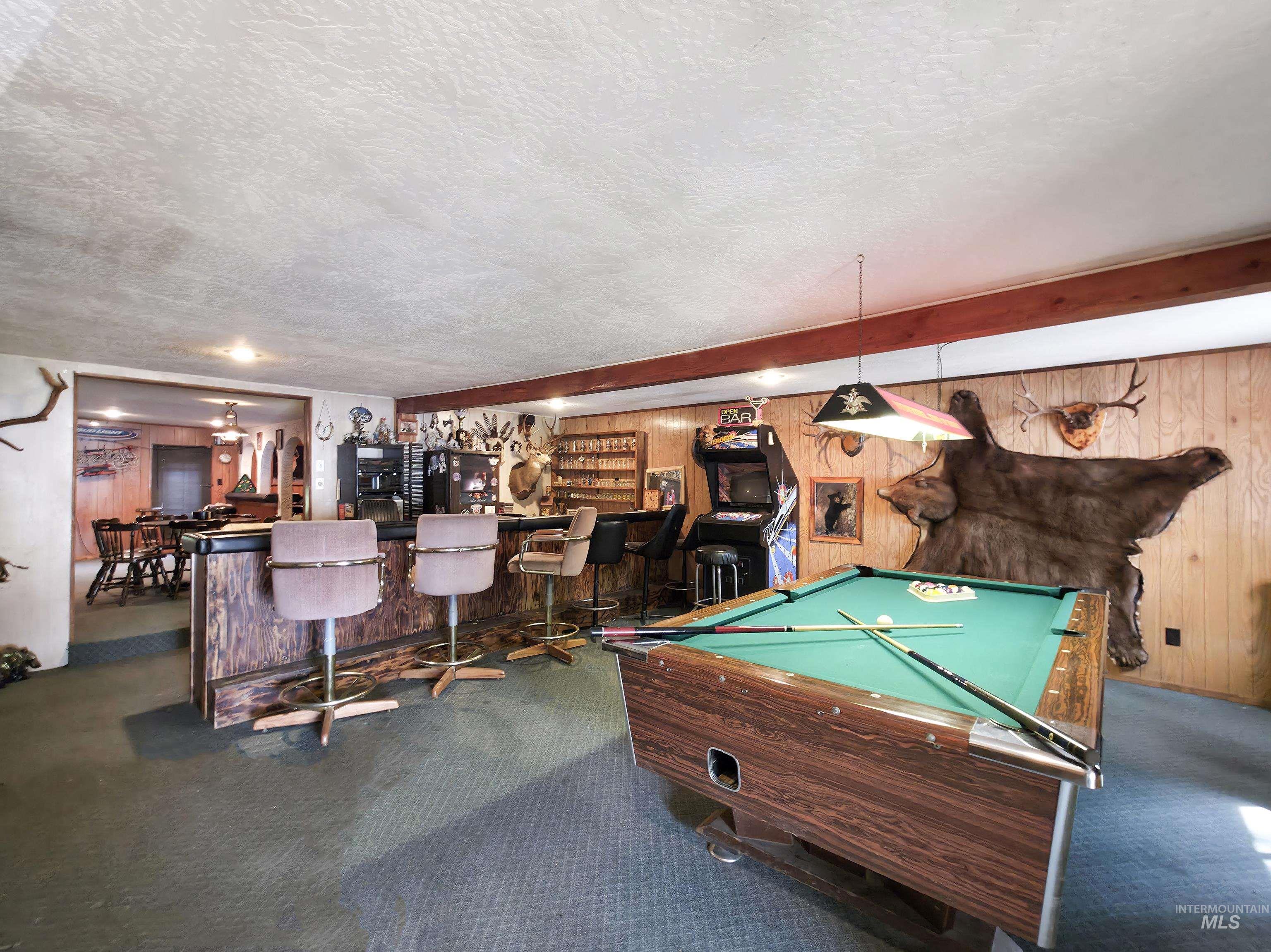 Rec room featuring game room, additional bedroom, wooden walls, pool table, and bar area