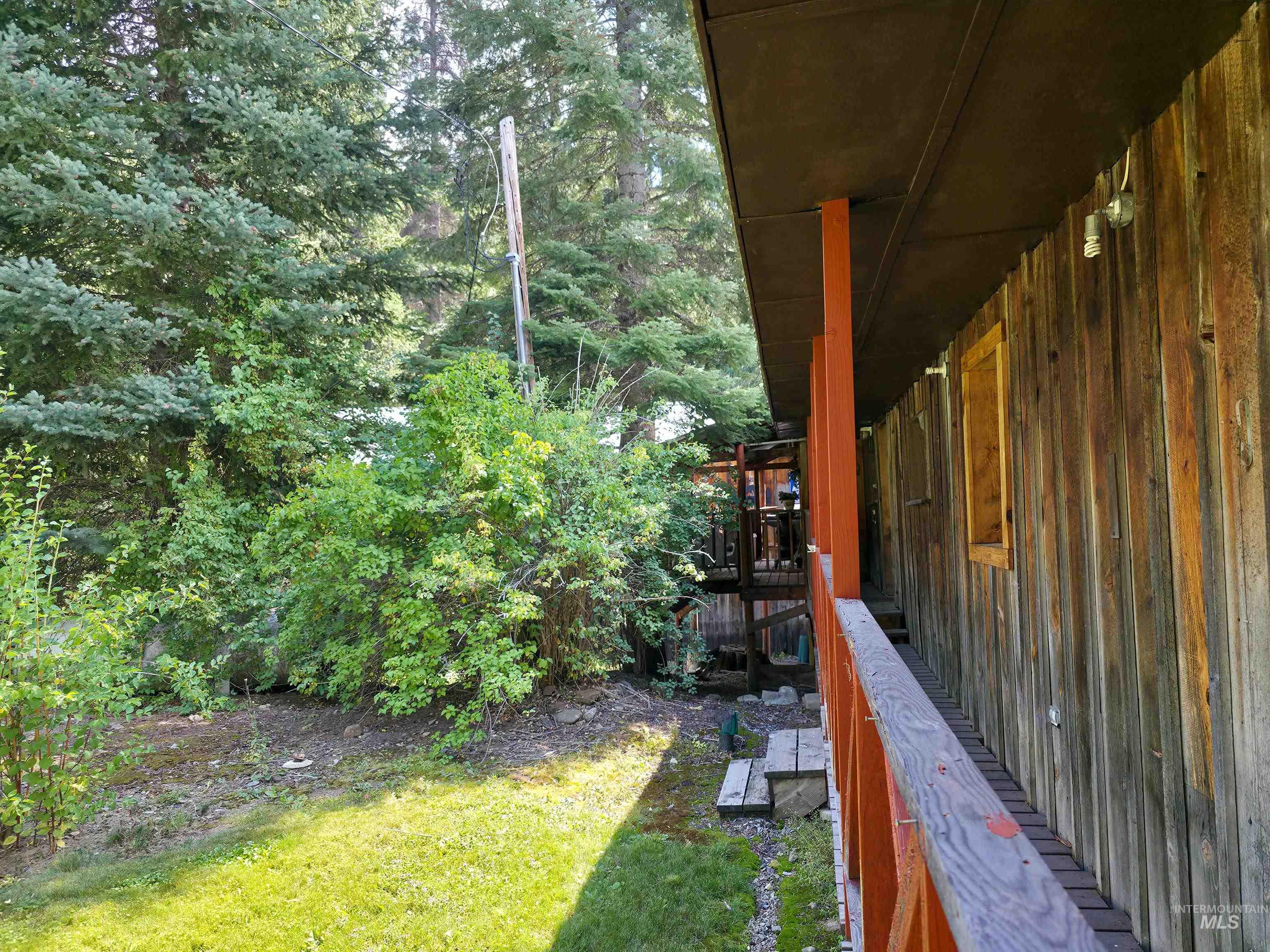View of green lawn featuring a deck and a view of trees