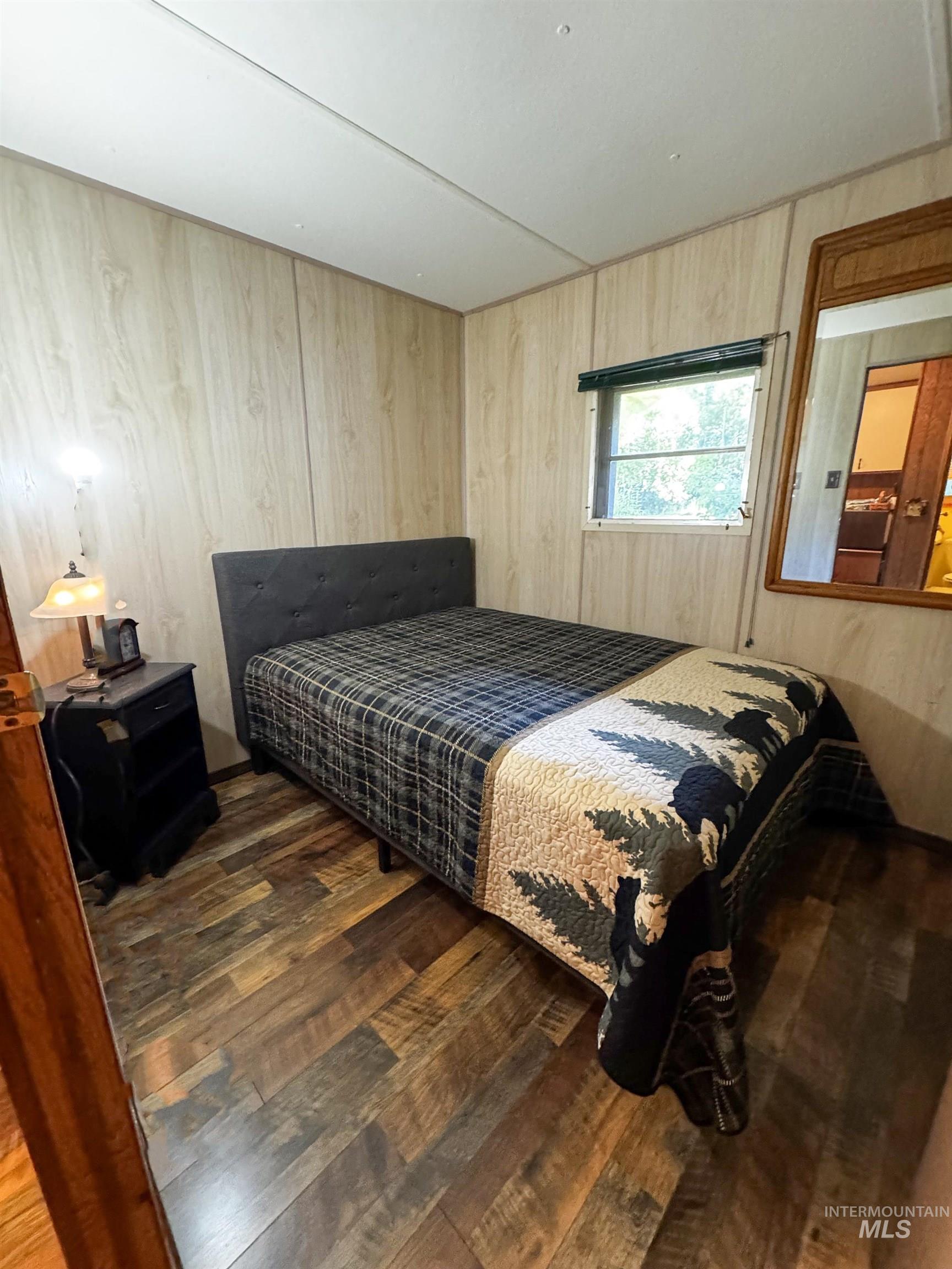 Bedroom featuring dark wood-type flooring and wood walls