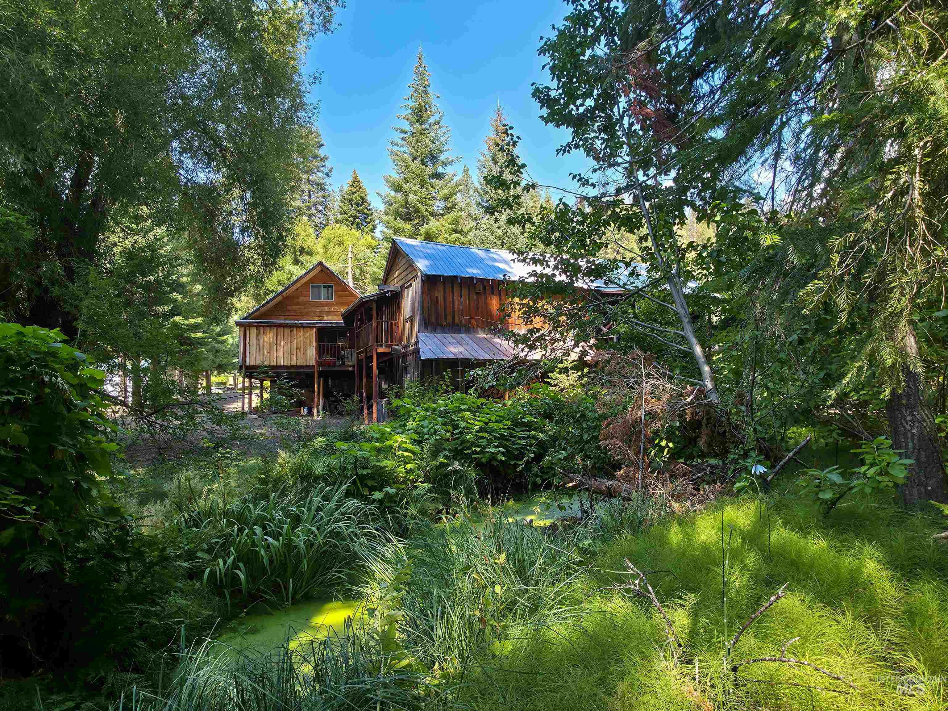 Rear view of house with a wooden deck, a metal roof, and a wooded view