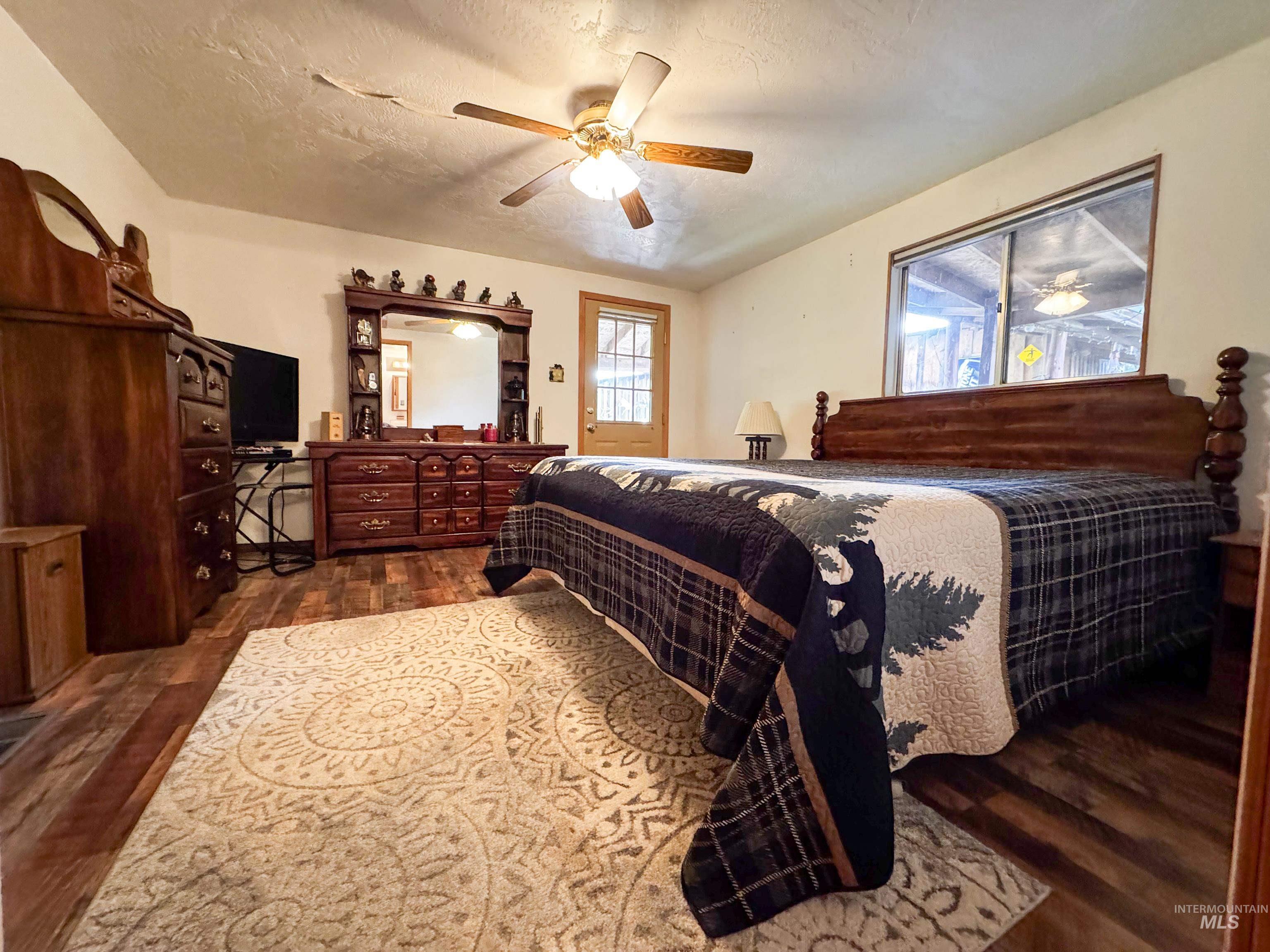 Bedroom with dark wood-type flooring, a textured ceiling, and ceiling fan