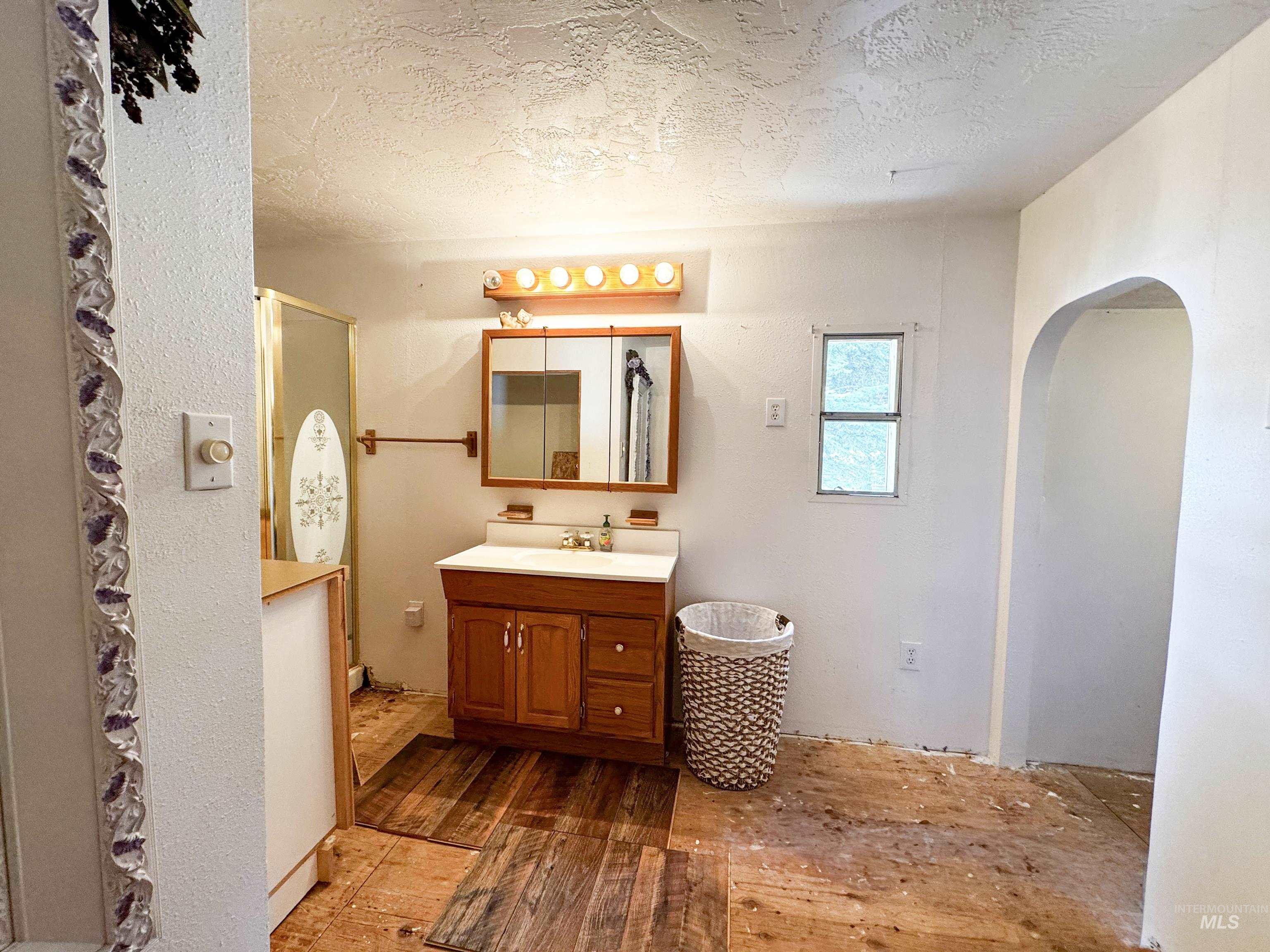 Bathroom with a textured ceiling, hardwood / wood-style floors, vanity, and a stall shower