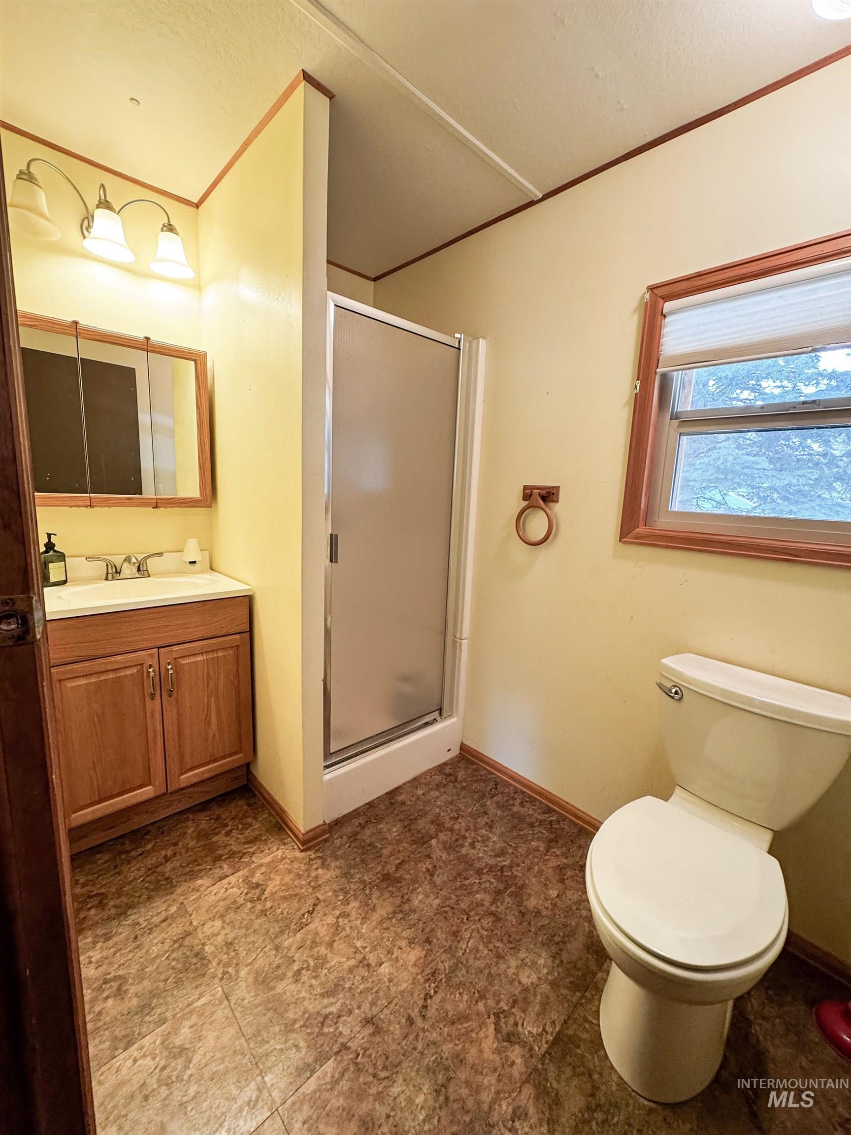 Bathroom with a shower stall, vanity, and ornamental molding