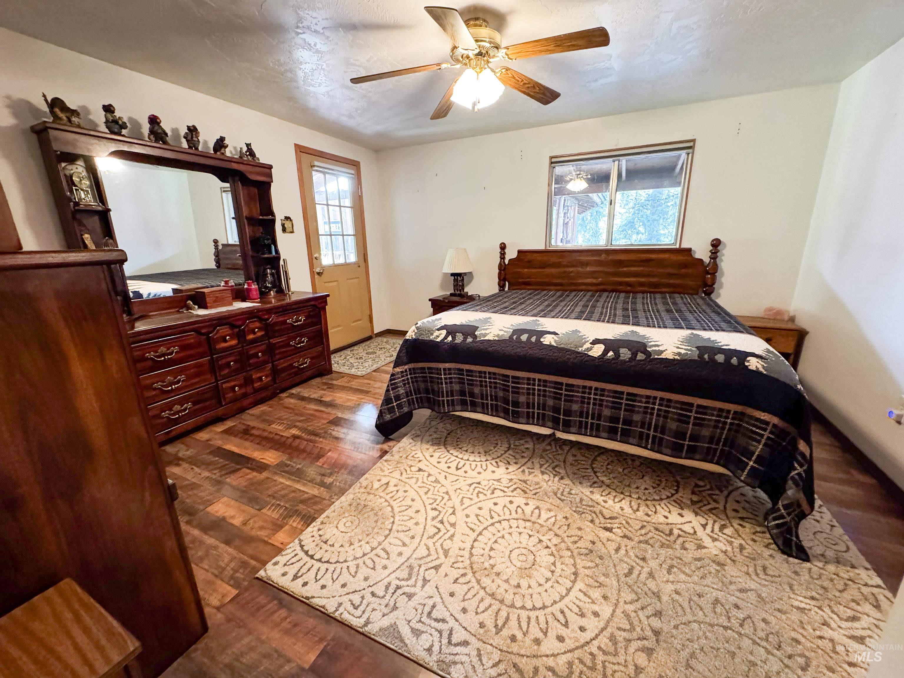 Bedroom with dark wood-style floors, ceiling fan, and a textured ceiling
