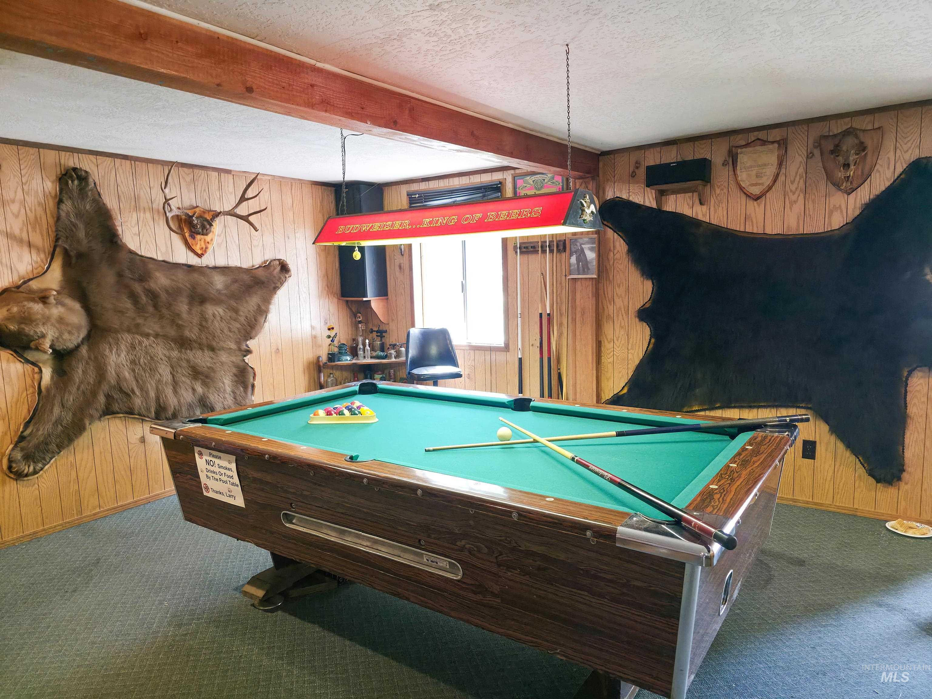 Rec room featuring wooden walls, carpet, a textured ceiling, beamed ceiling, and billiards