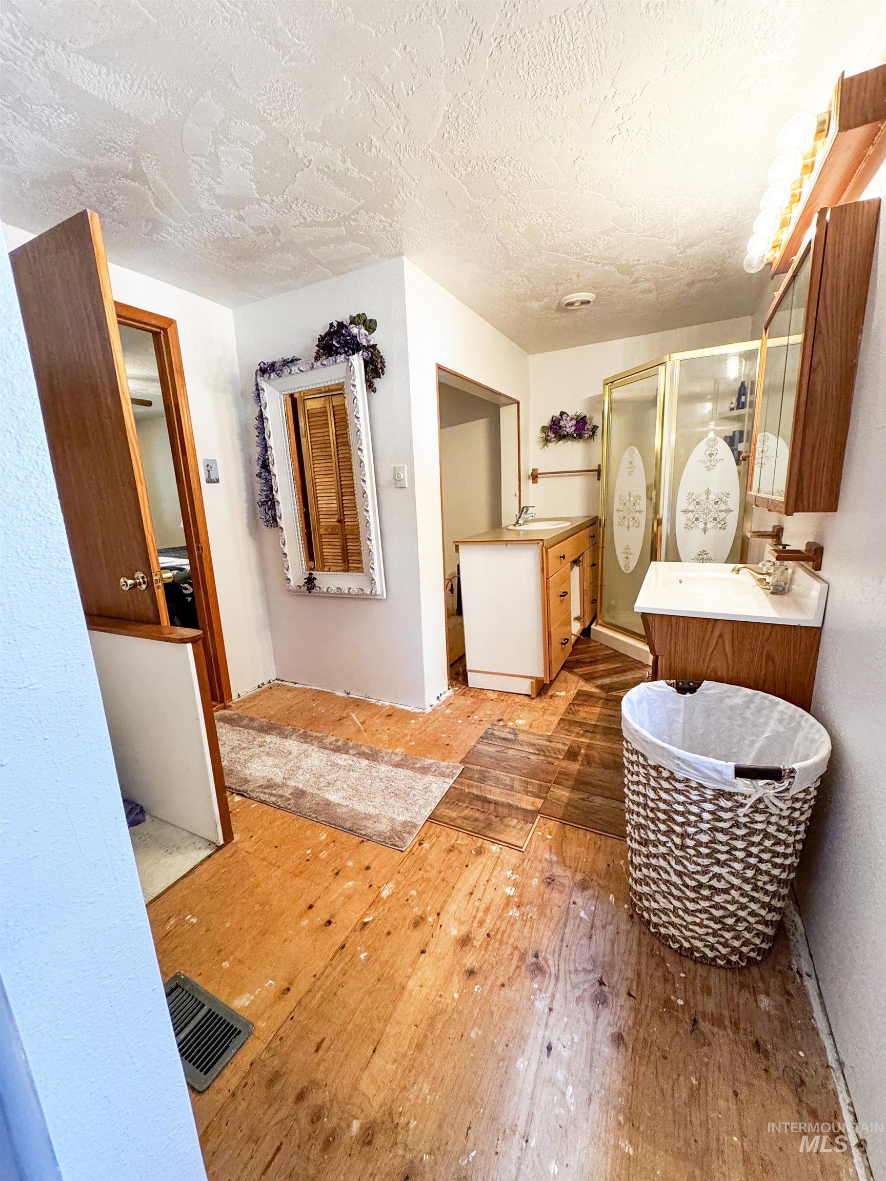 Full bath featuring hardwood / wood-style floors, a shower stall, vanity, and a textured ceiling