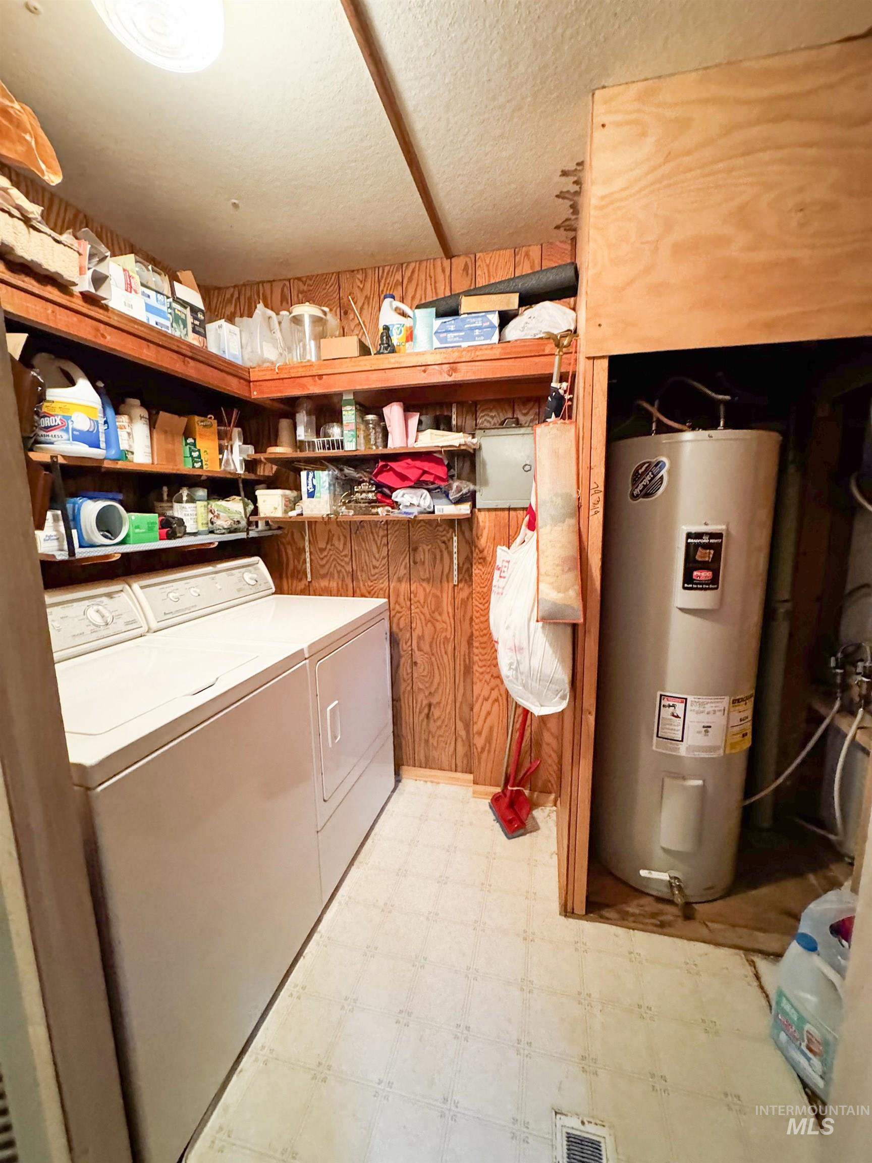 Washroom featuring light floors, electric water heater, and washing machine and dryer