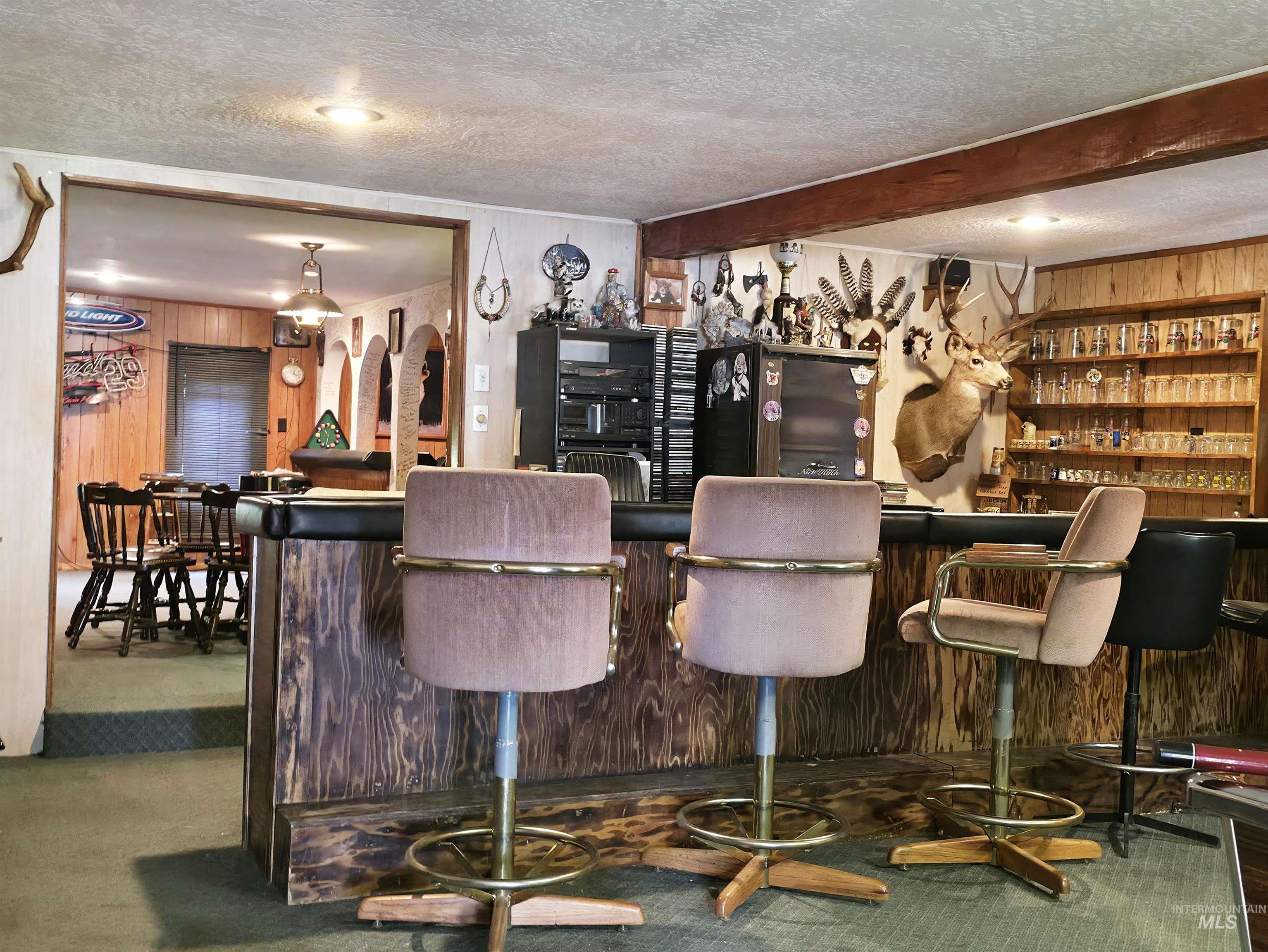 Indoor dry bar featuring wood walls and a textured ceiling