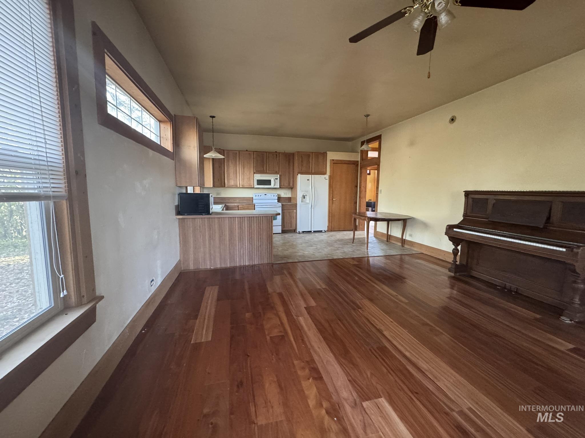 Unfurnished living room featuring dark wood finished floors and ceiling fan