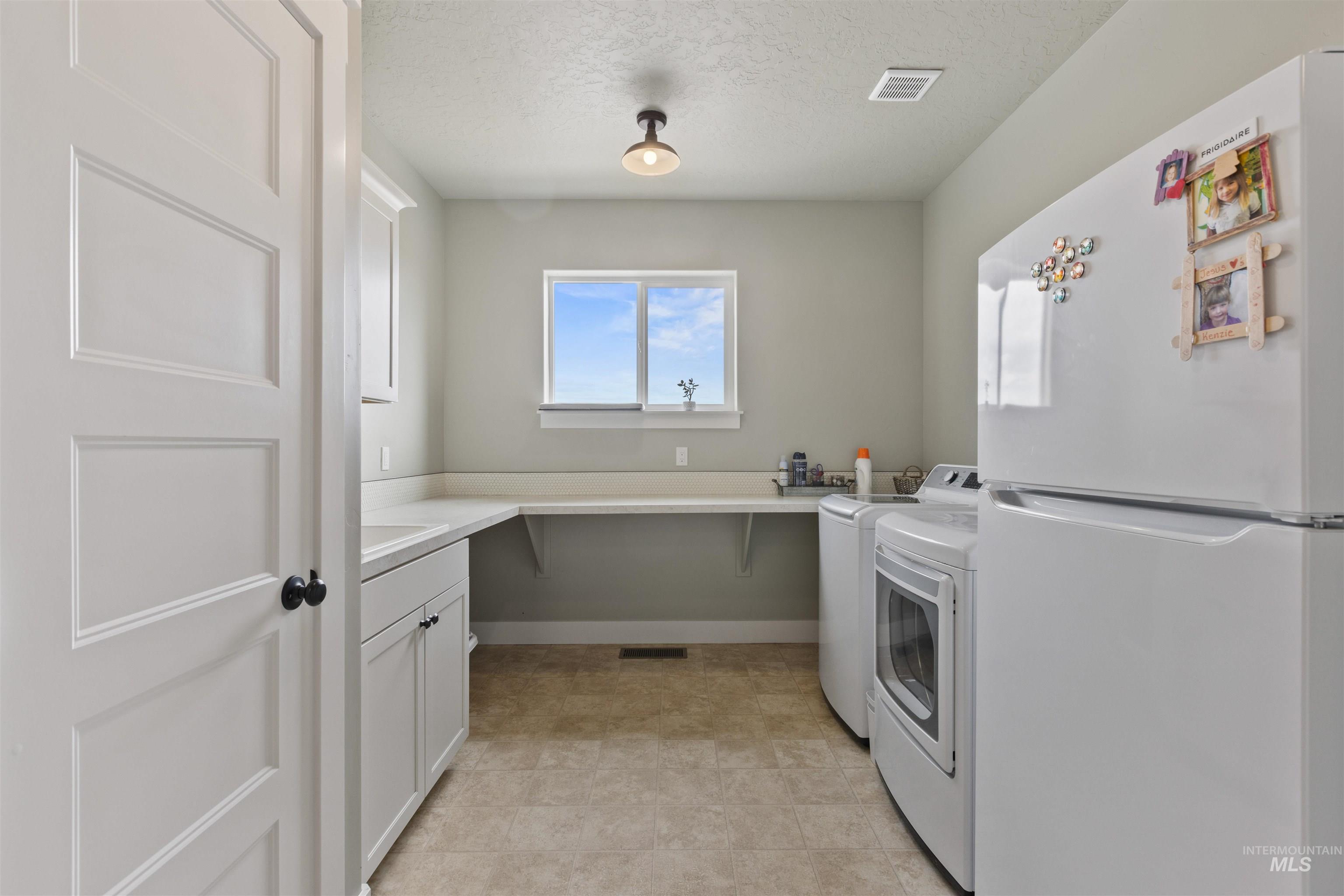 Laundry area with washer and dryer, cabinet space, and a textured ceiling