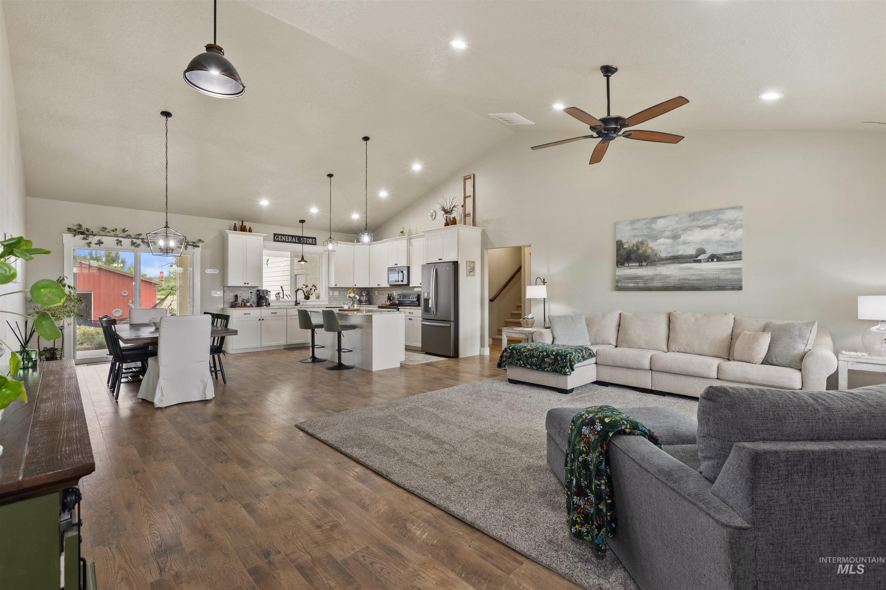Living room featuring a ceiling fan, high vaulted ceiling, stairs, wood finished floors, and recessed lighting