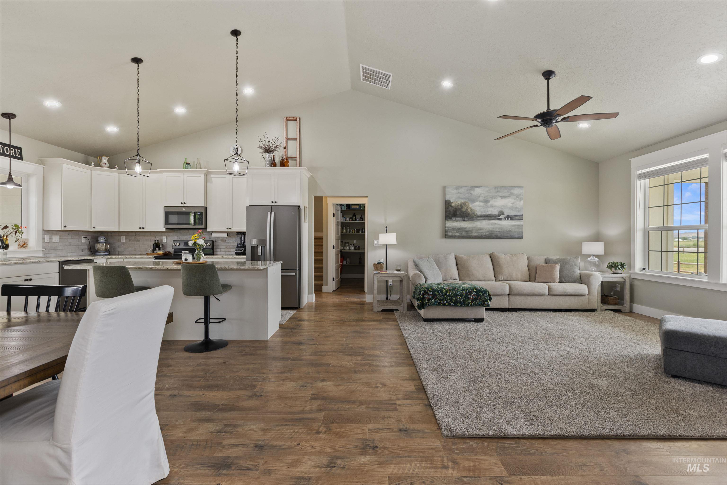 Living room featuring healthy amount of natural light, dark wood-type flooring, a ceiling fan, recessed lighting, and high vaulted ceiling