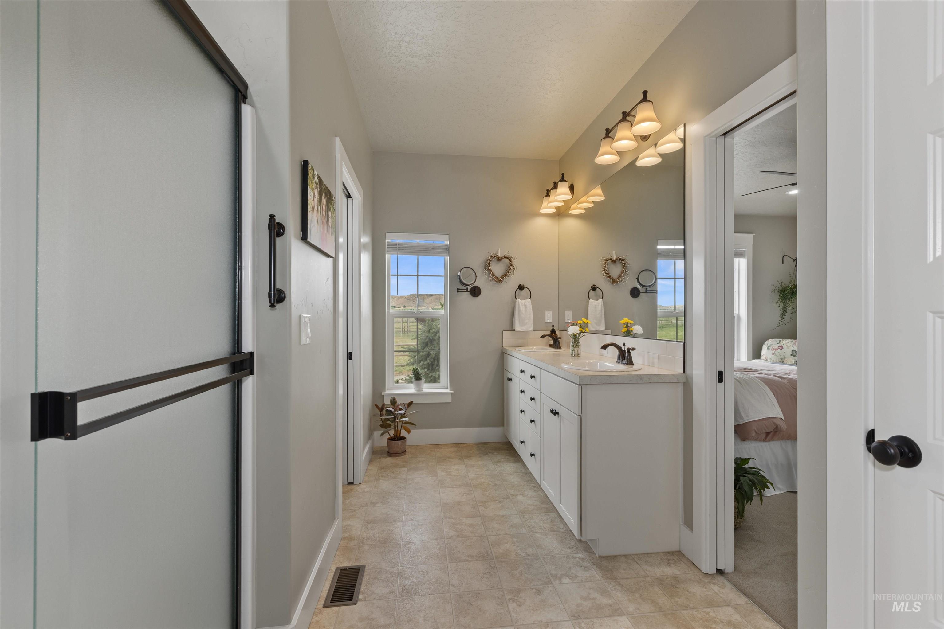 Bathroom featuring double vanity, ensuite bath, and a textured ceiling