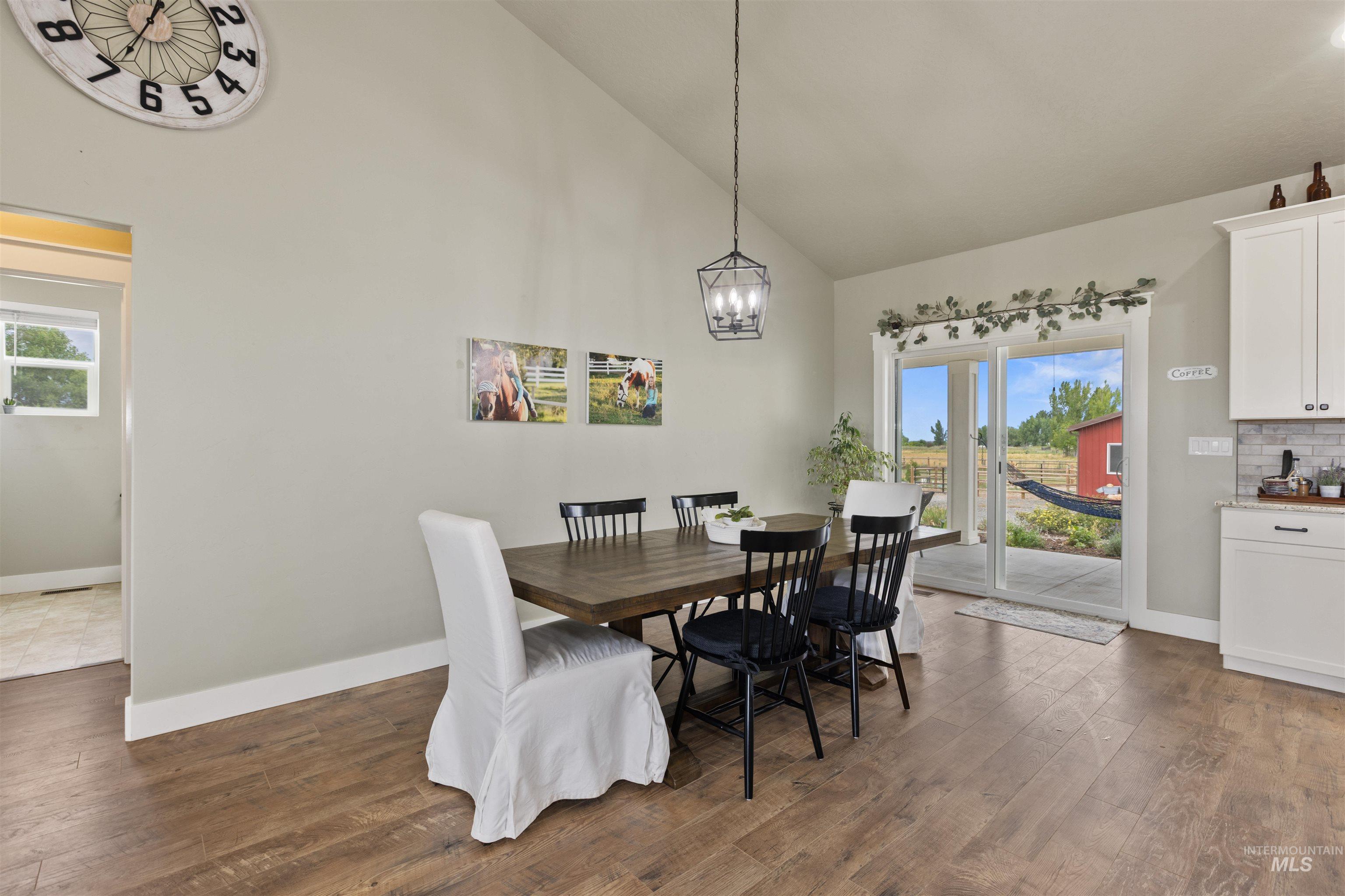 Dining area featuring high vaulted ceiling, dark wood-style flooring, a chandelier, and plenty of natural light