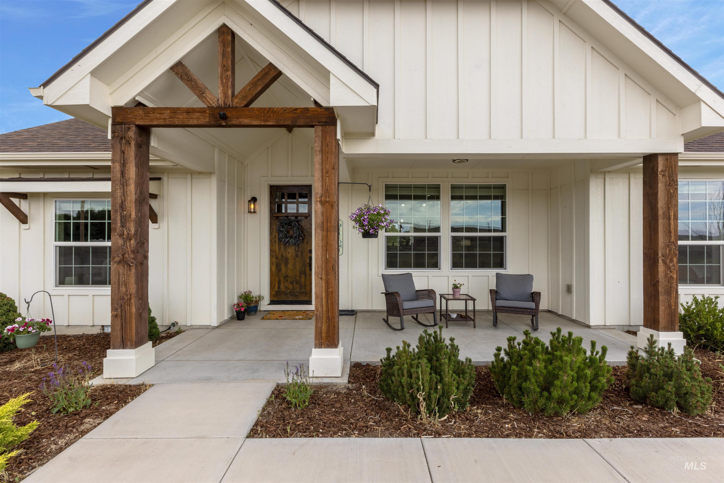 Property entrance with covered porch, board and batten siding, and a shingled roof
