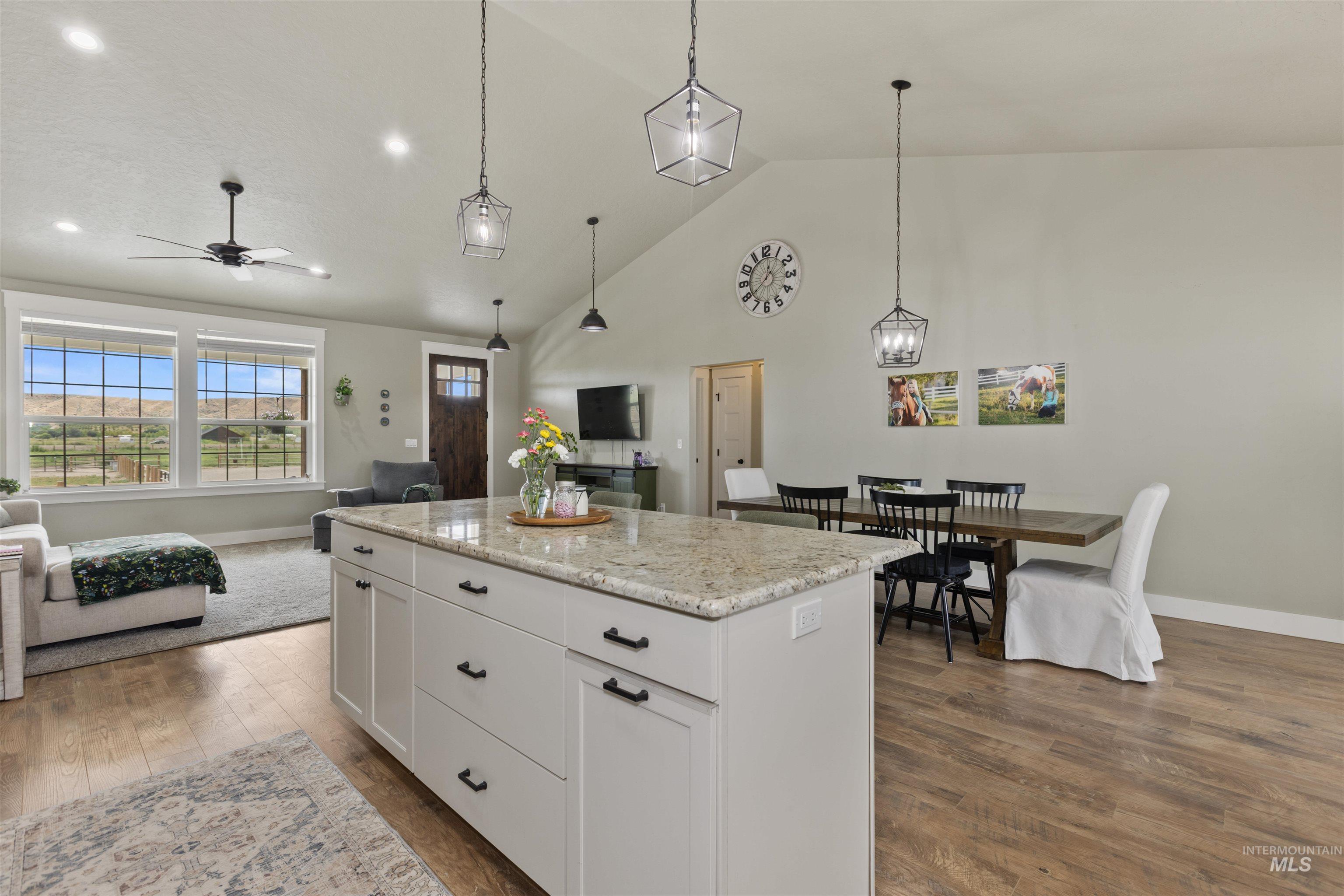 Kitchen featuring open floor plan, high vaulted ceiling, dark wood-style floors, a center island, and ceiling fan