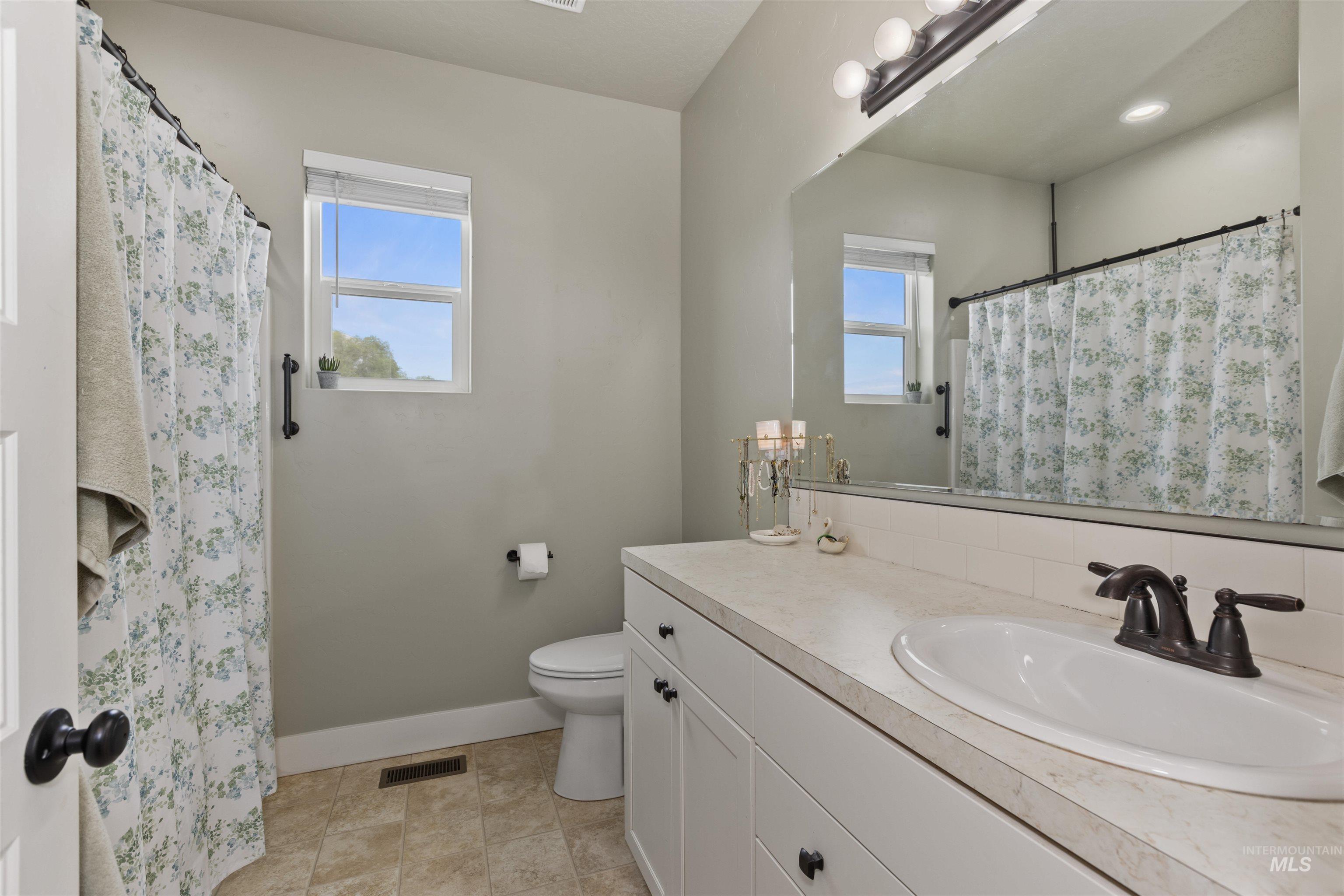 Bathroom featuring vanity, tasteful backsplash, and curtained shower