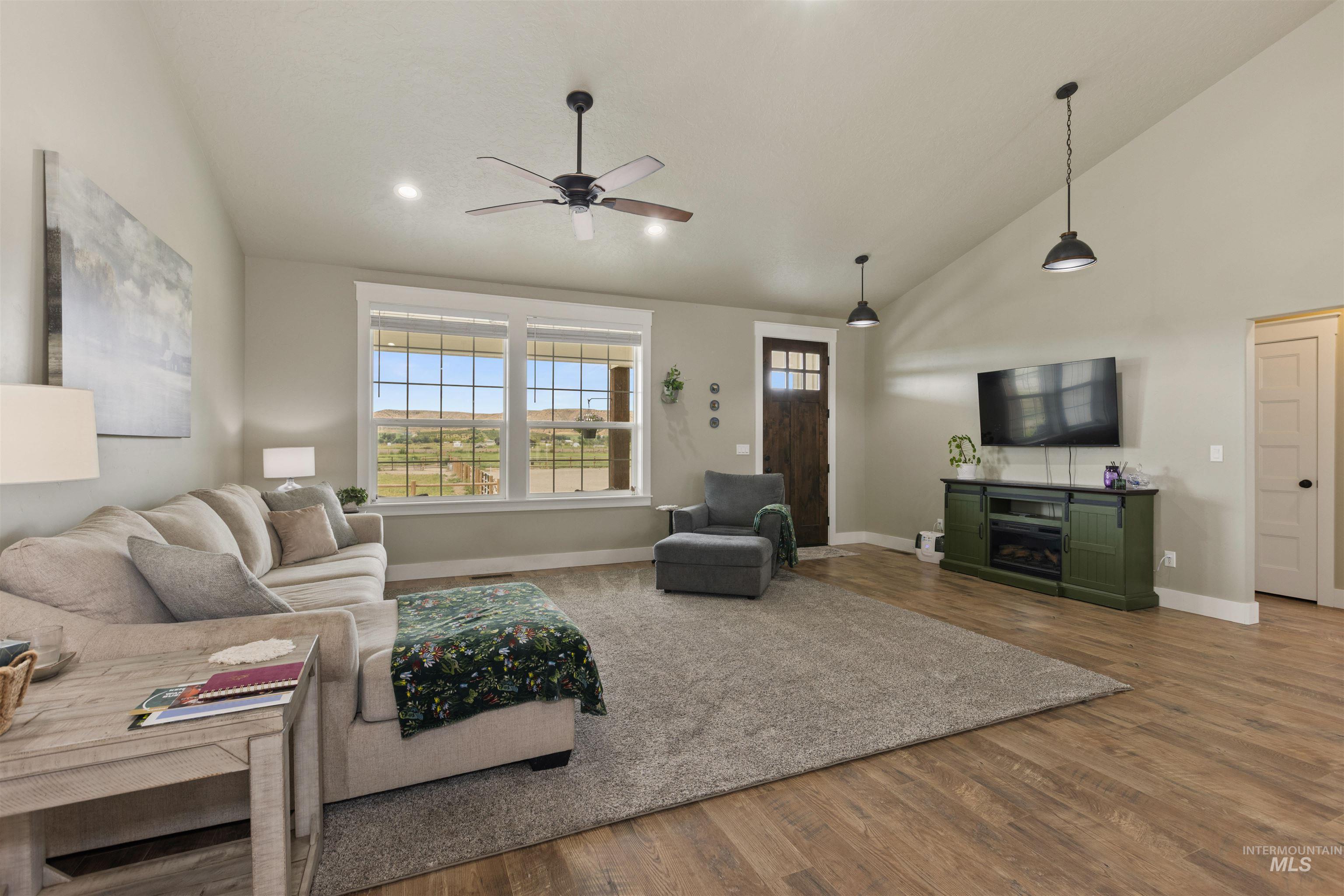 Living area featuring ceiling fan, wood finished floors, and high vaulted ceiling