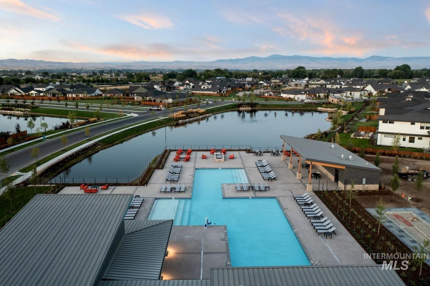 Aerial view at dusk of a water and mountain view, a residential view, and view of pool area