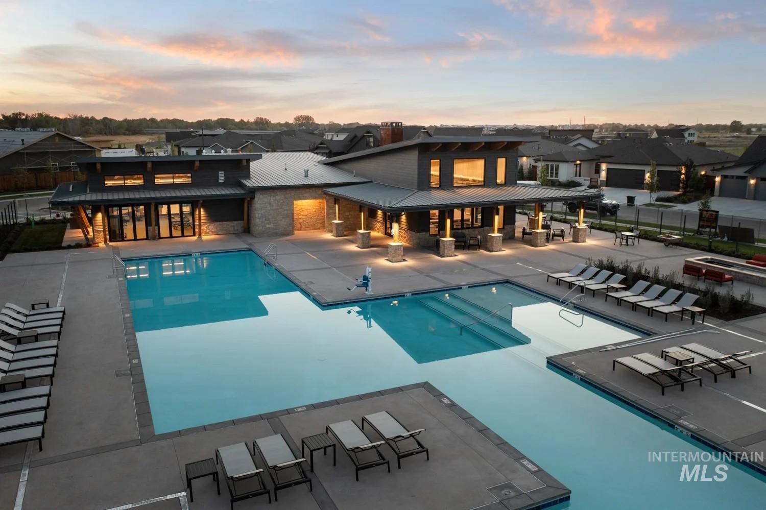 Pool at dusk featuring a community pool, a patio, and a residential view