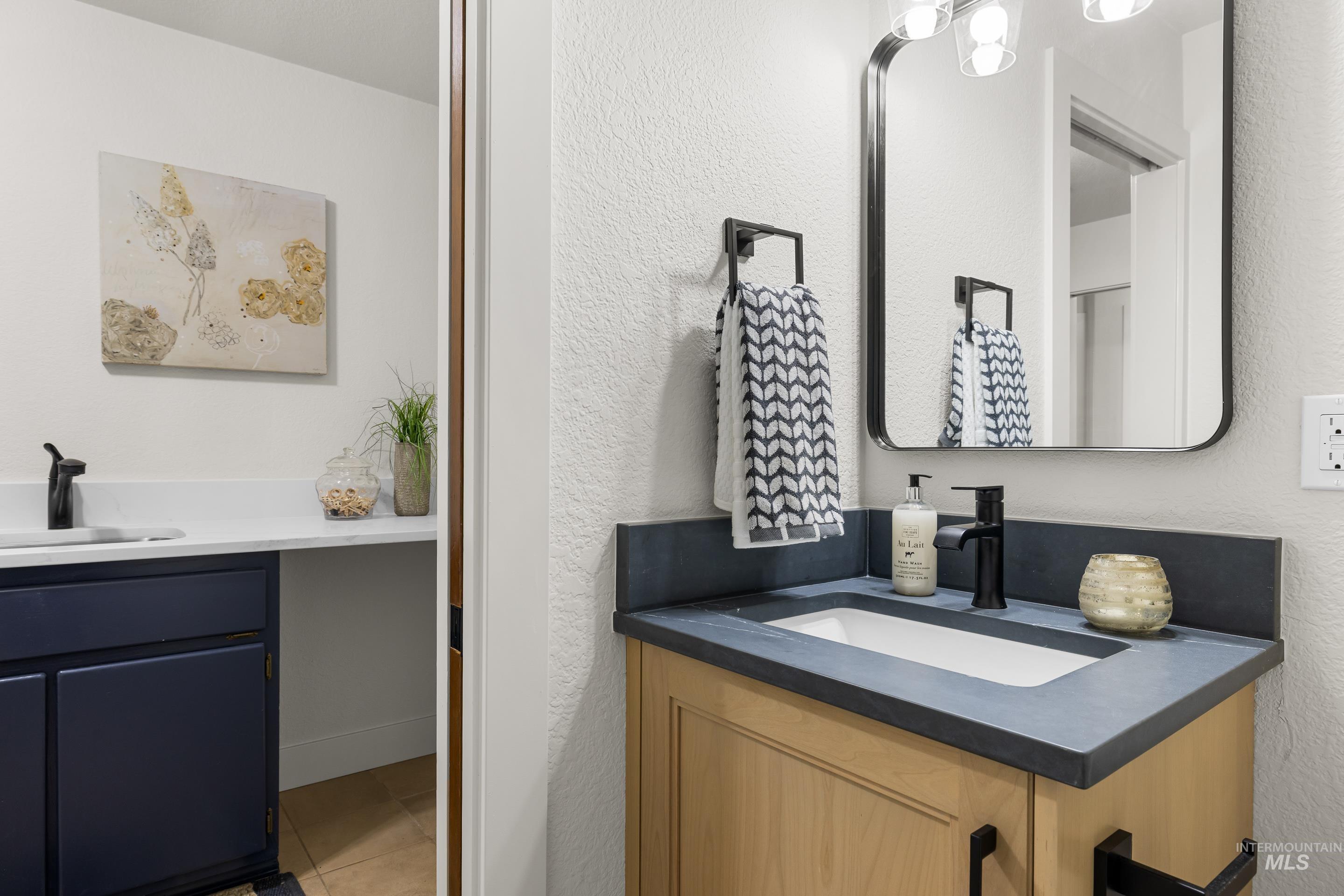 Bathroom featuring vanity, a textured wall, and light tile patterned floors