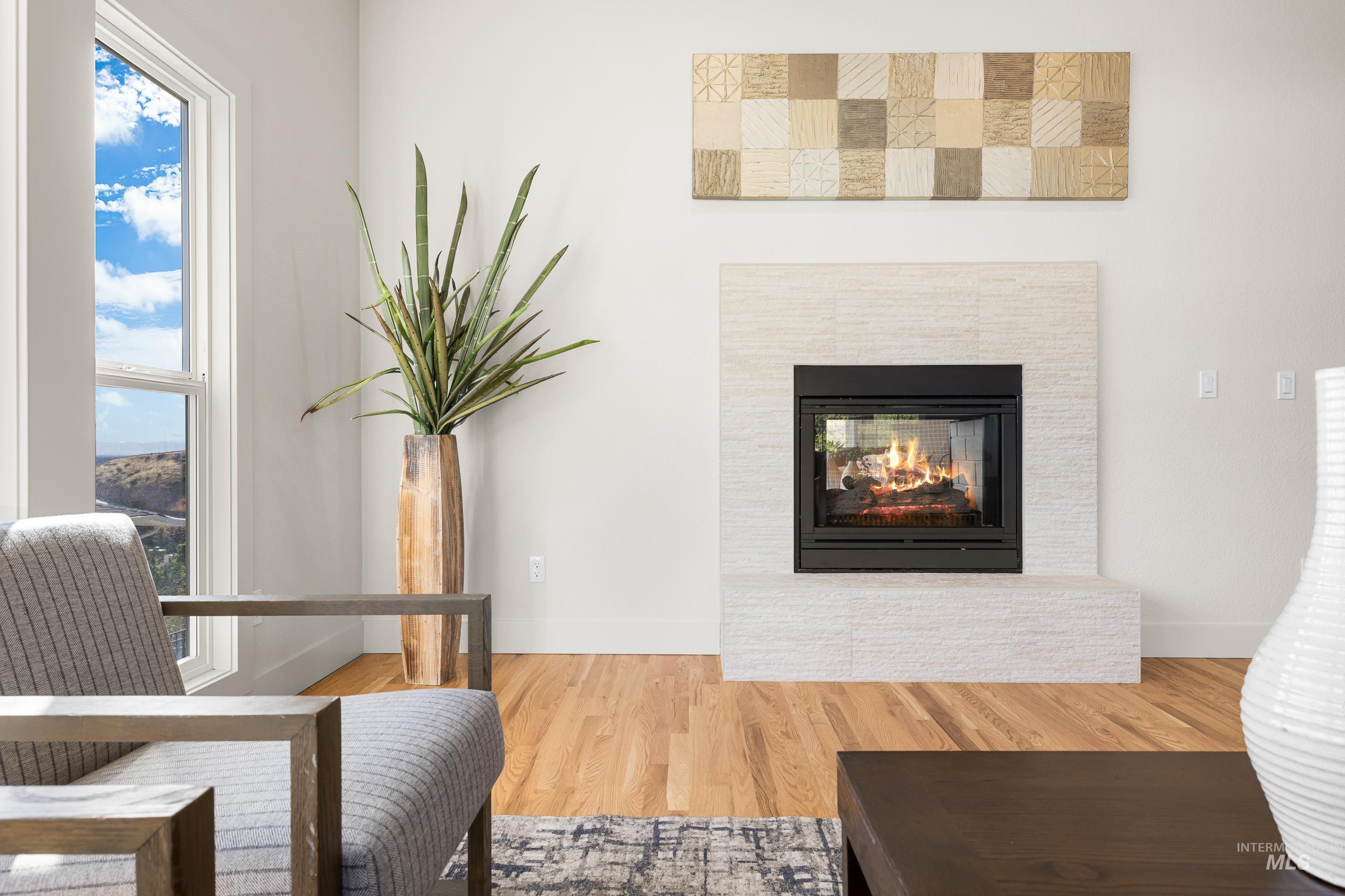 Sitting room with wood finished floors, a multi sided fireplace, and healthy amount of natural light