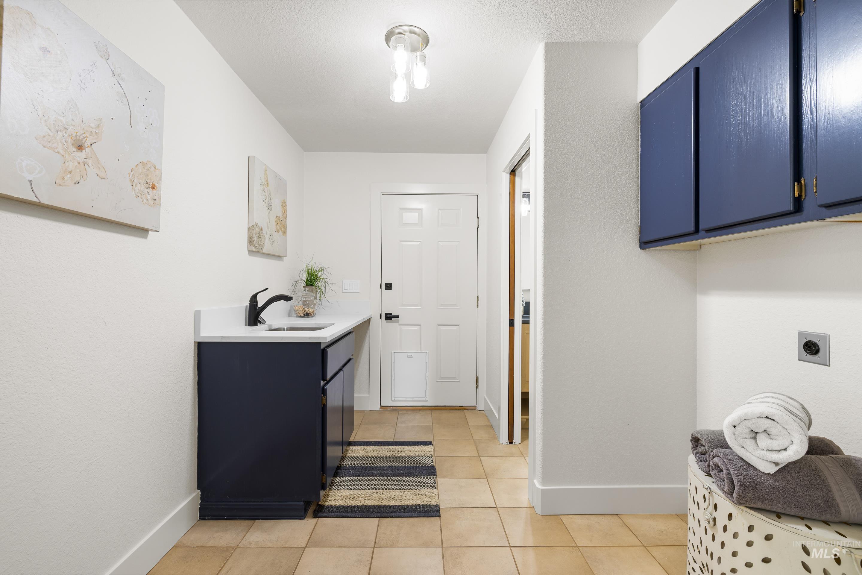 Washroom featuring light tile patterned flooring, cabinet space, and hookup for an electric dryer