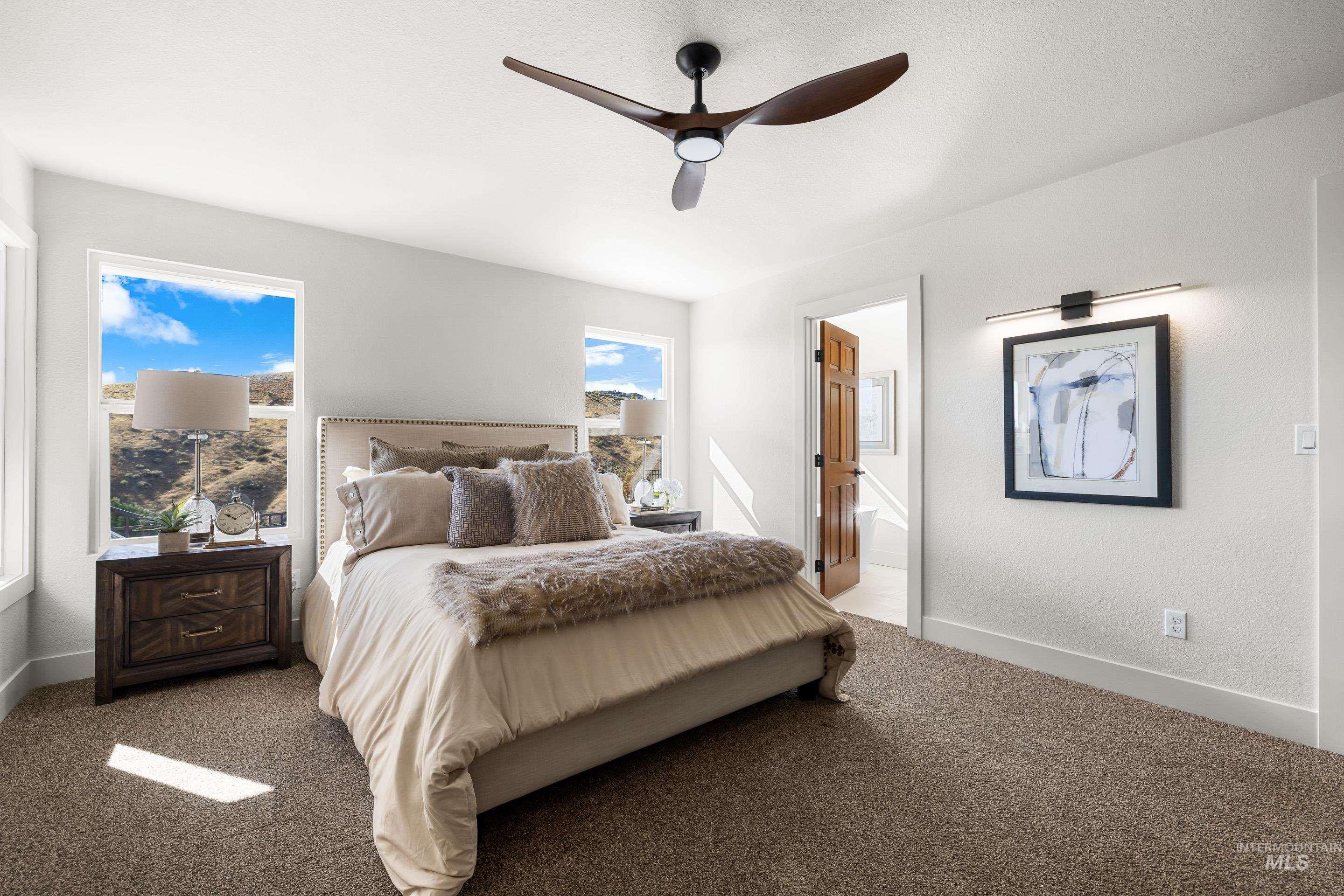 Carpeted bedroom featuring a ceiling fan and ensuite bath