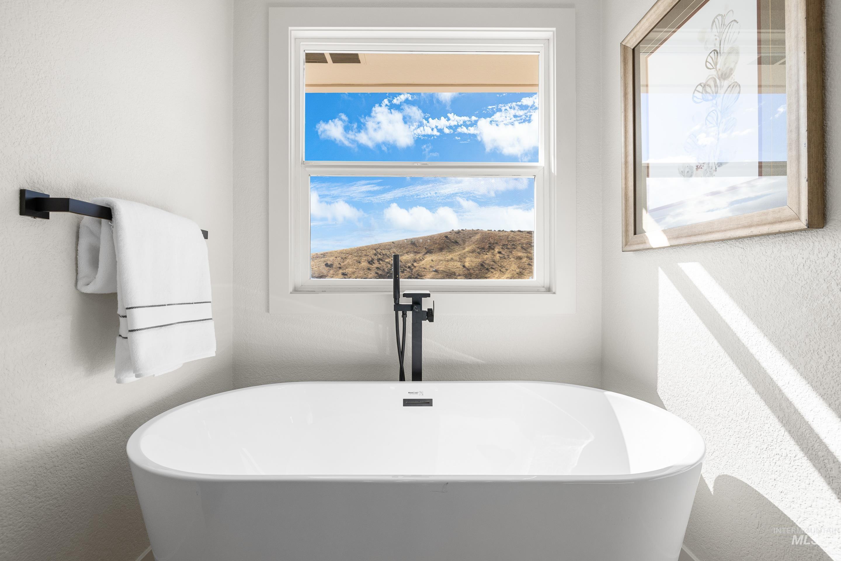 Full bath featuring a textured wall and a freestanding tub