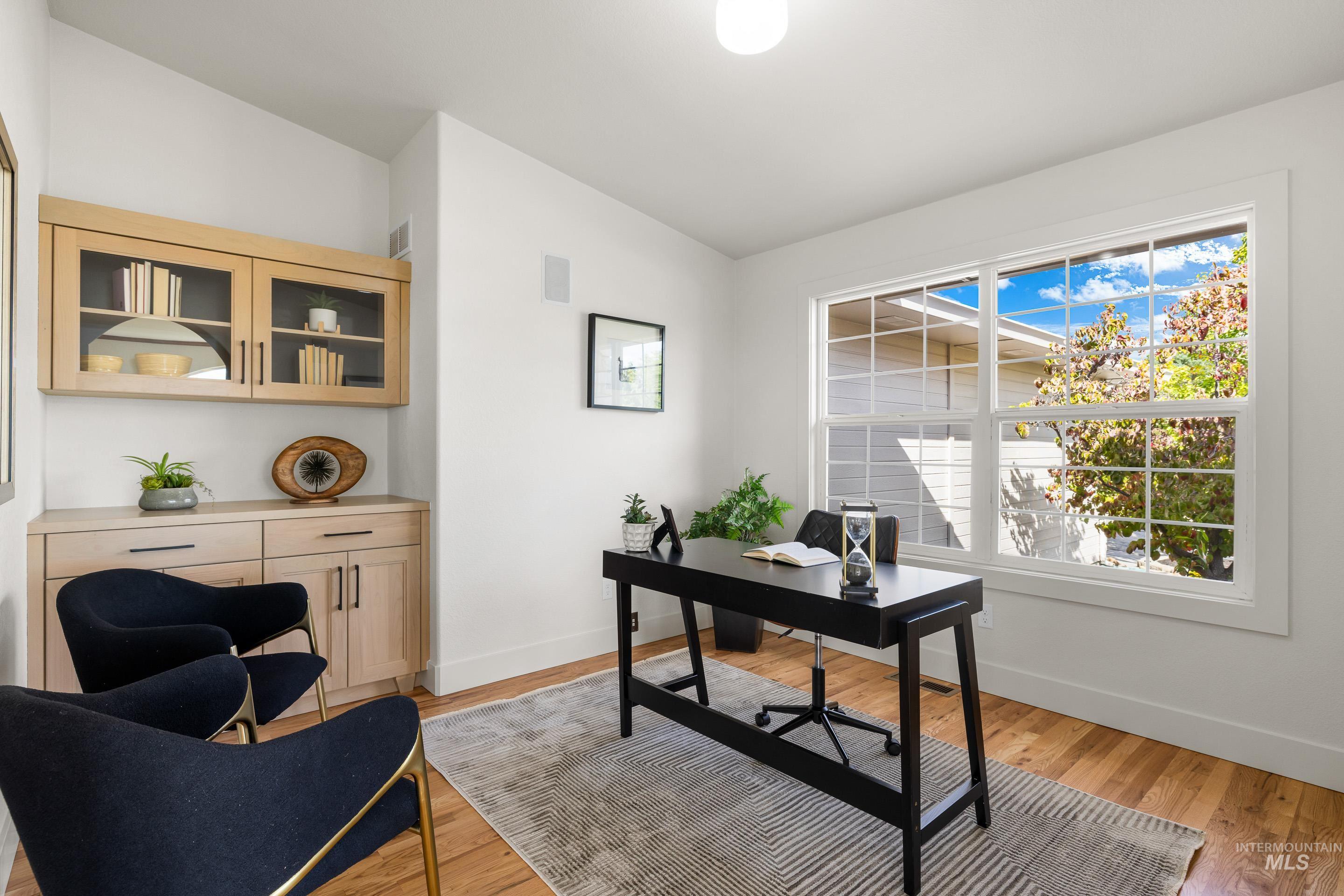 Office area with light wood-style floors and vaulted ceiling