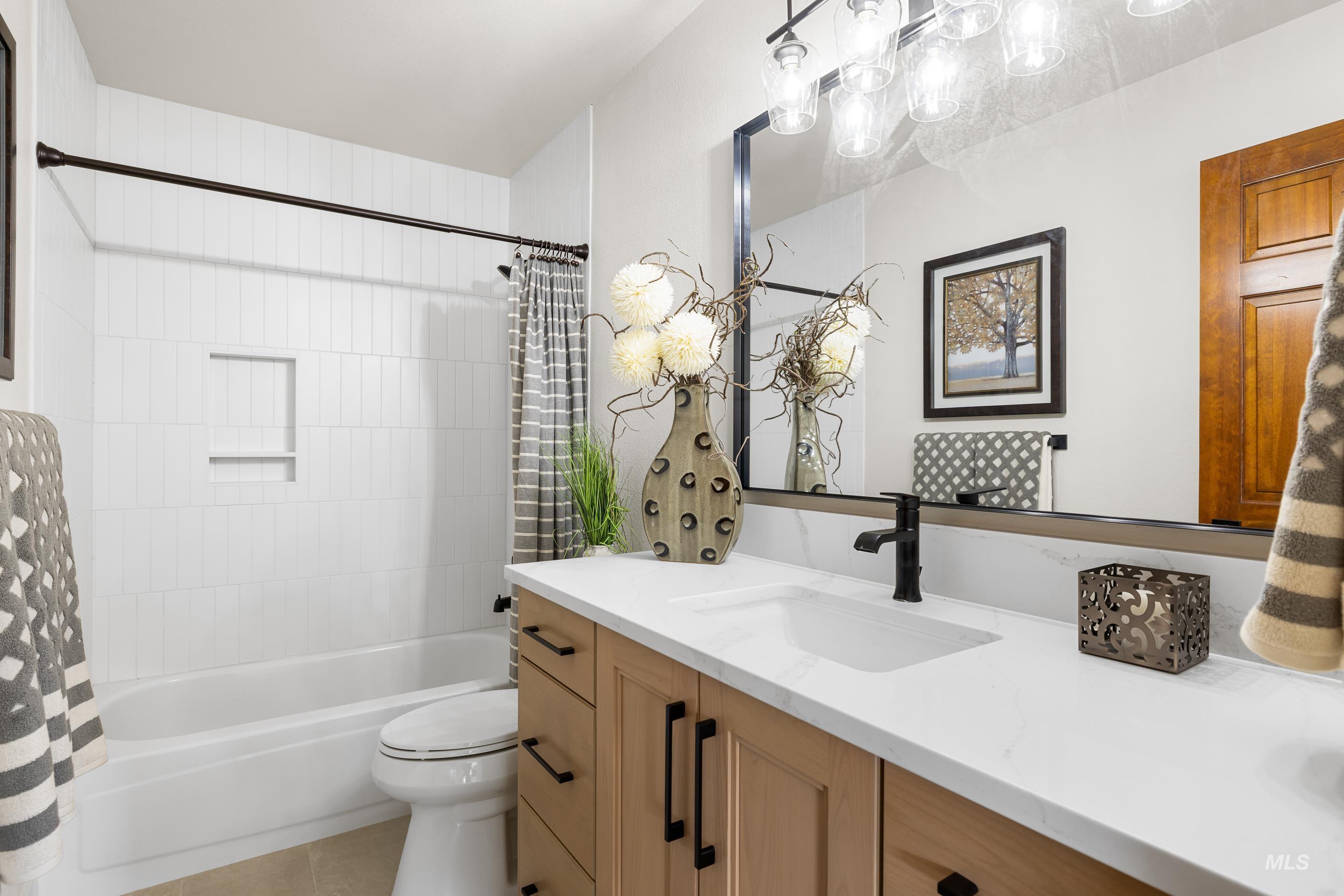 Bathroom featuring shower / tub combo, vanity, and light tile patterned floors