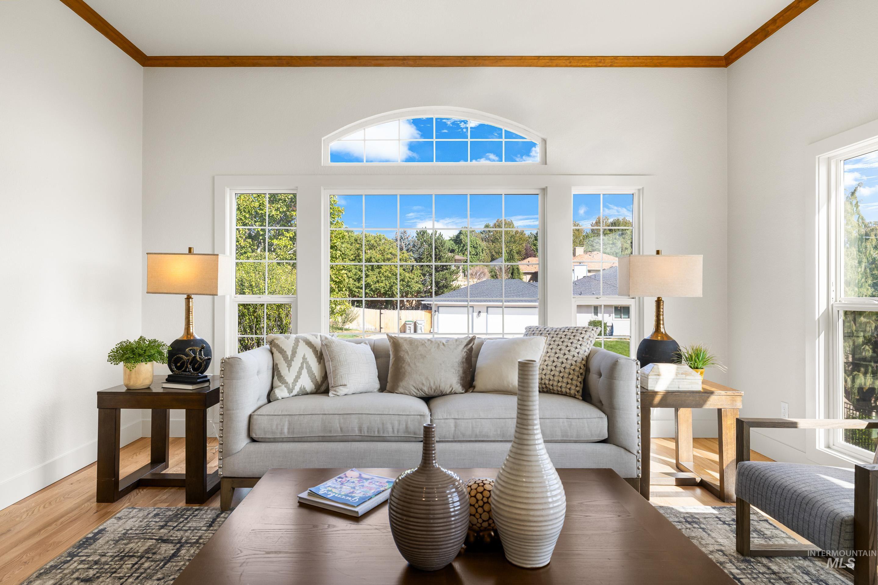 Living room with healthy amount of natural light, crown molding, and wood finished floors