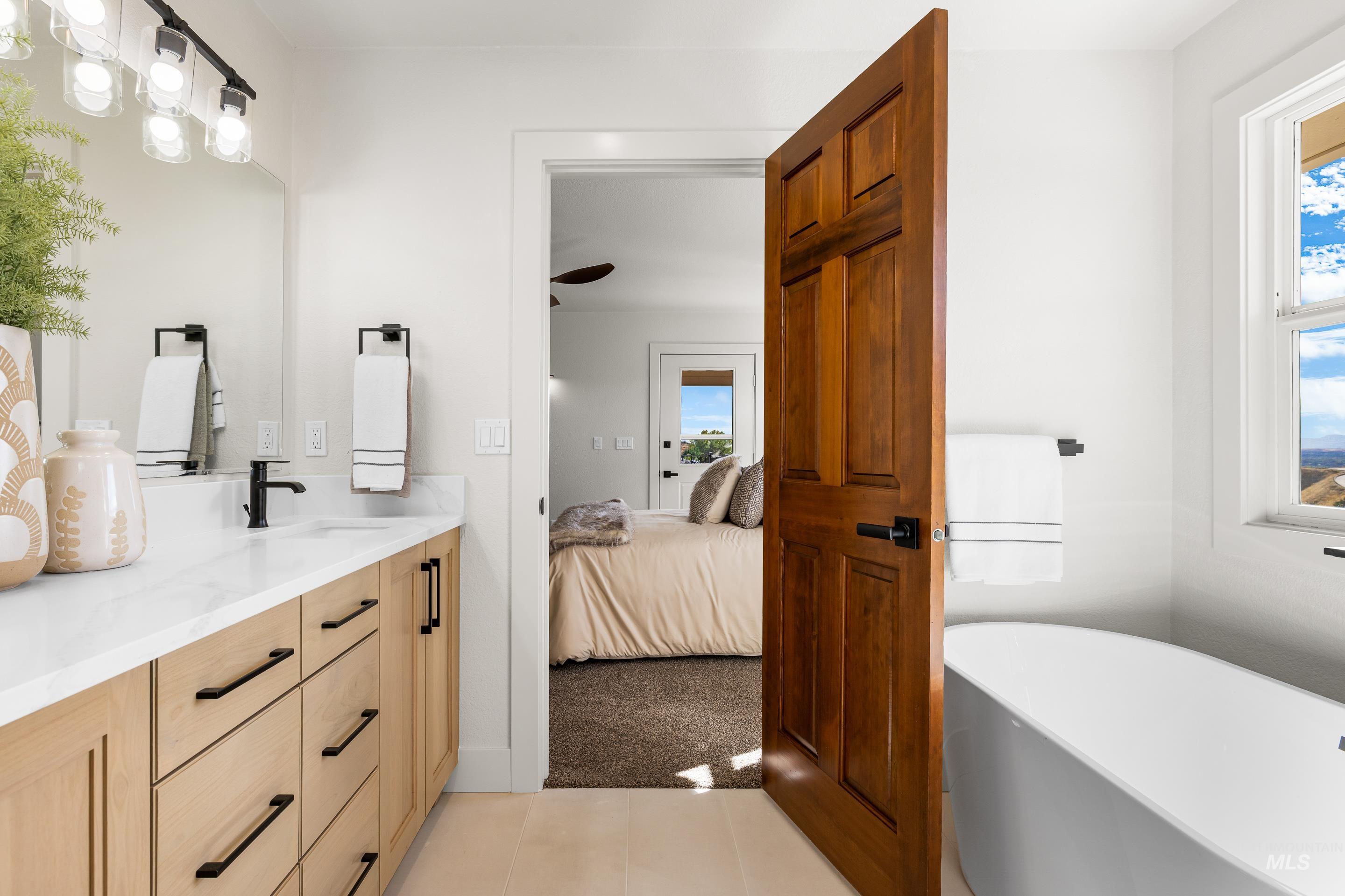 Bathroom with vanity, a soaking tub, light colored carpet, connected bathroom, and light tile patterned floors