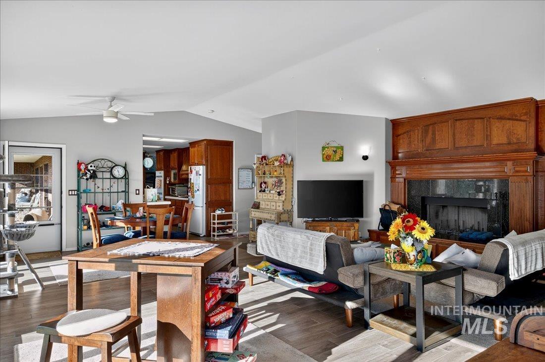 Living room featuring lofted ceiling, wood finished floors, a fireplace, and ceiling fan