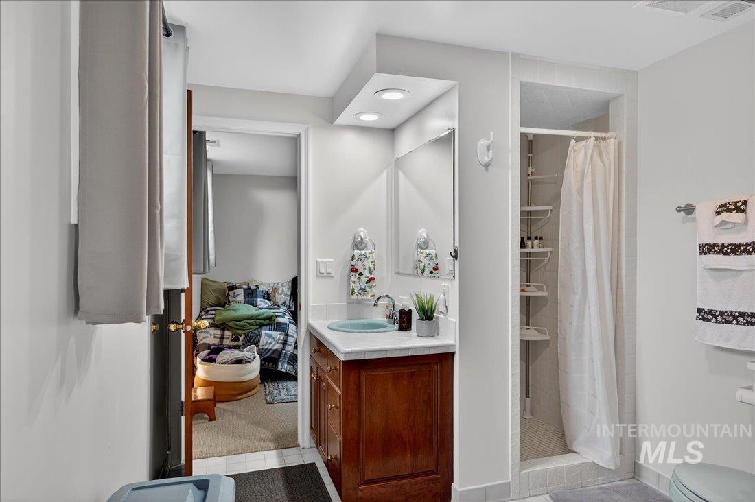 Bathroom with a shower stall, vanity, light tile patterned floors, ensuite bathroom, and recessed lighting
