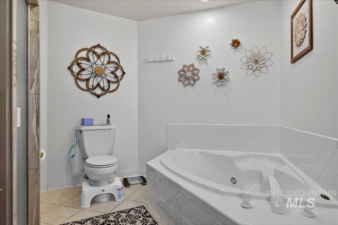 Full bath with a jetted tub and light tile patterned flooring