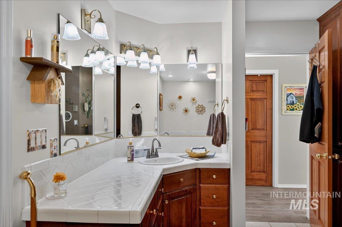 Full bath with vanity, light wood-style flooring, and decorative backsplash