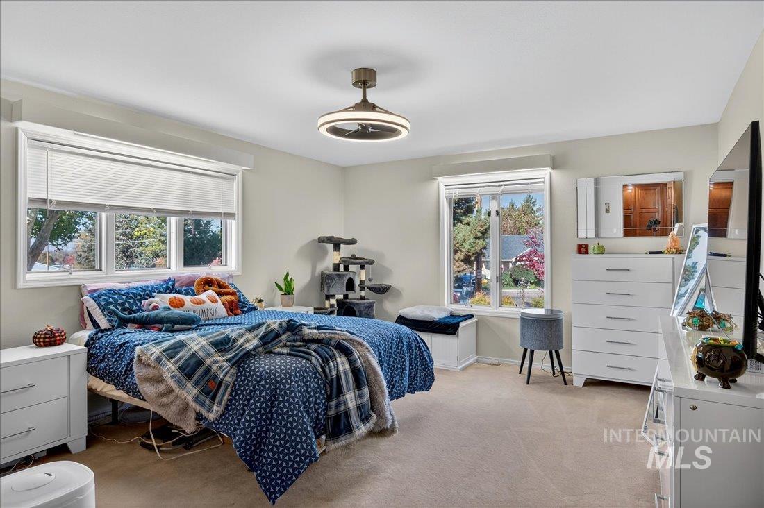 Bedroom featuring light colored carpet and multiple windows