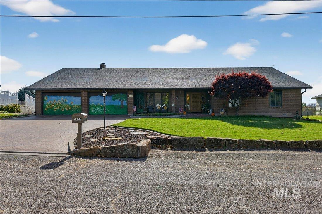 Single story home with decorative driveway, a front lawn, brick siding, roof with shingles, and an attached garage