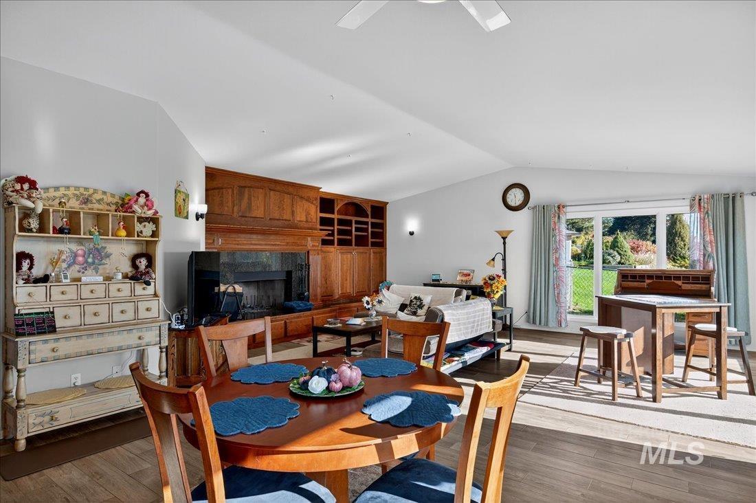 Dining area with wood finished floors, vaulted ceiling, and a high end fireplace