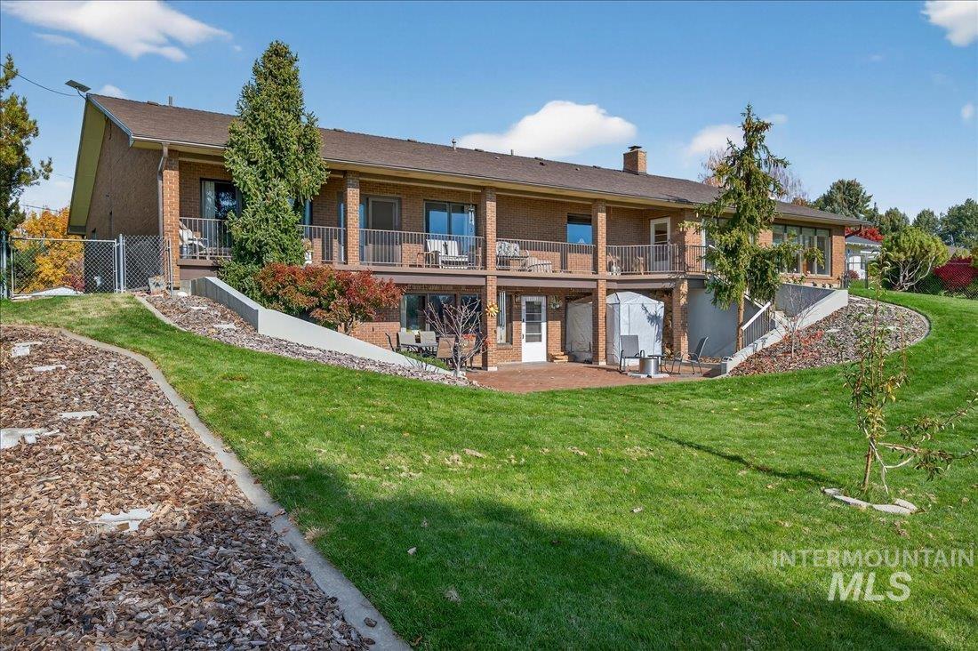 Rear view of property with brick siding, a patio, a lawn, and a chimney
