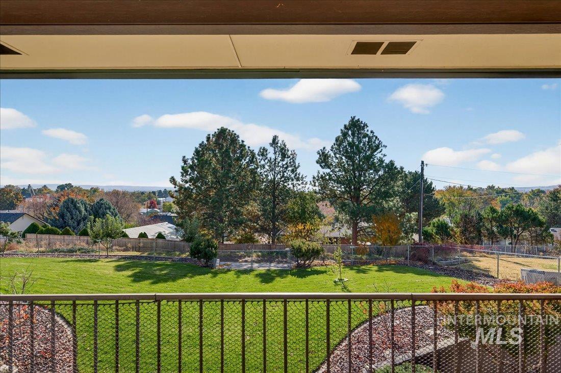 View of community featuring a fenced backyard, a balcony, and view of scattered trees